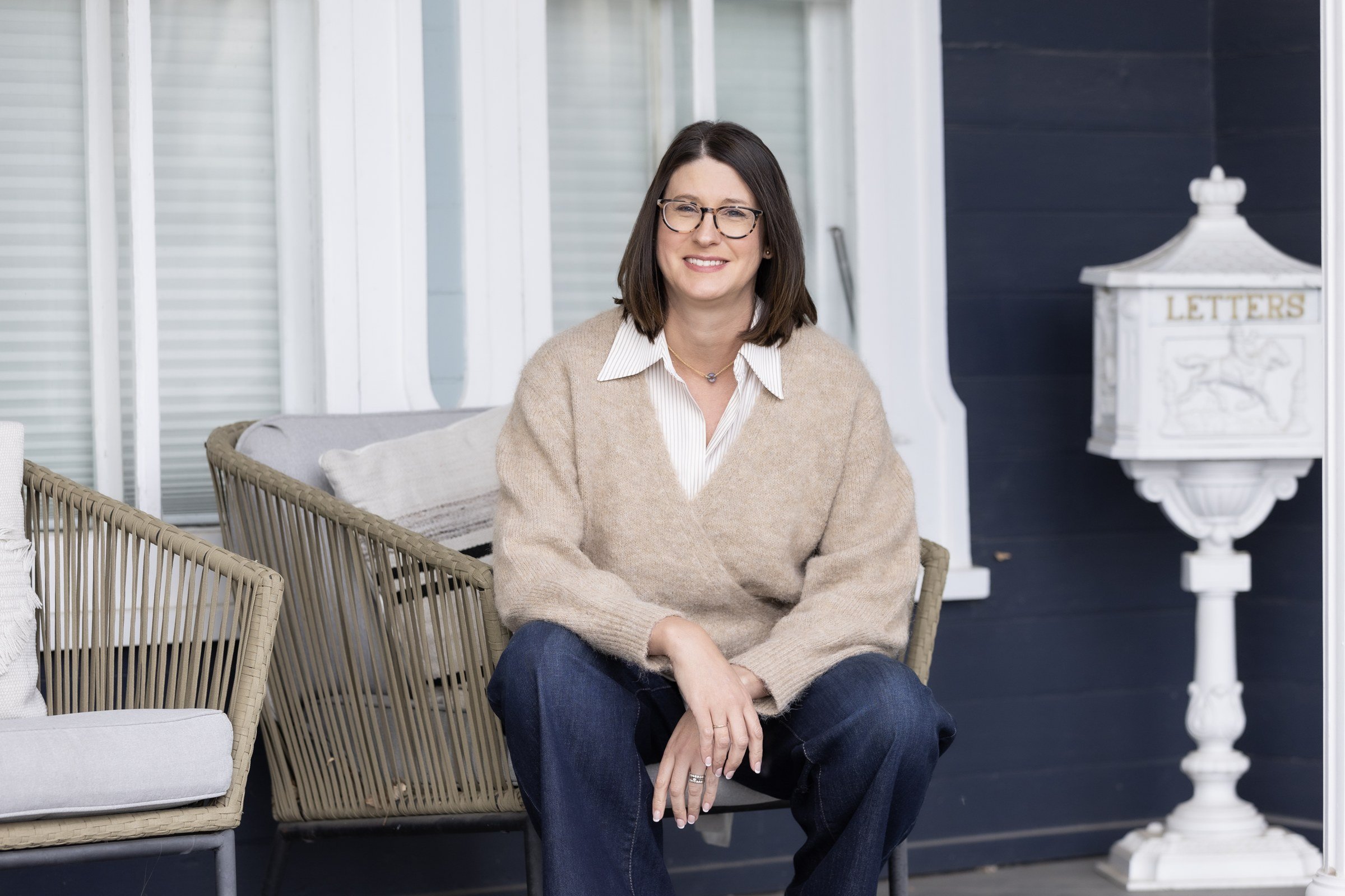 Jill Decker, LPCC, seated on a navy porch beside a white letterbox