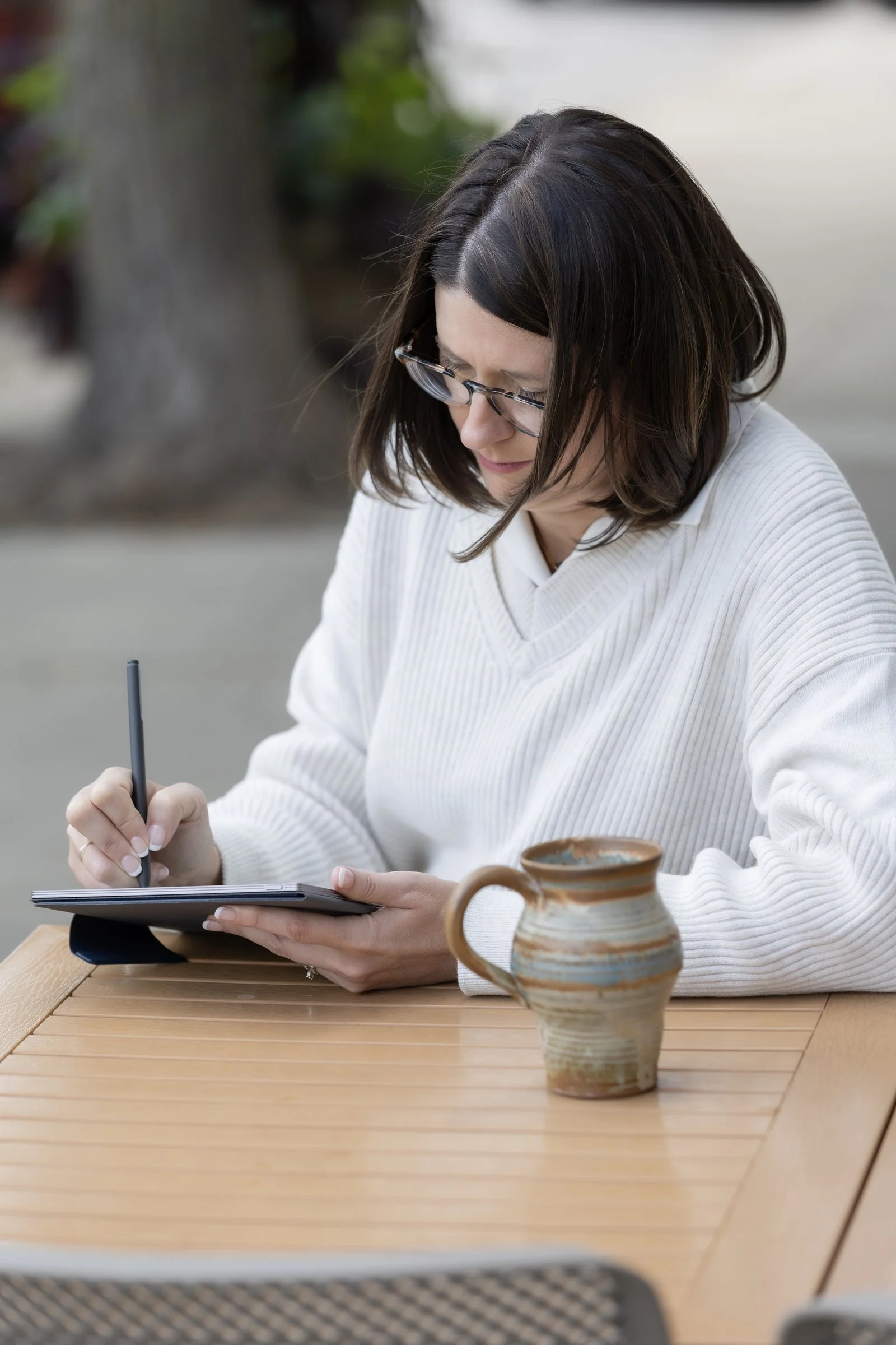 Jill Decker, LPCC, writing reflectively at a café table