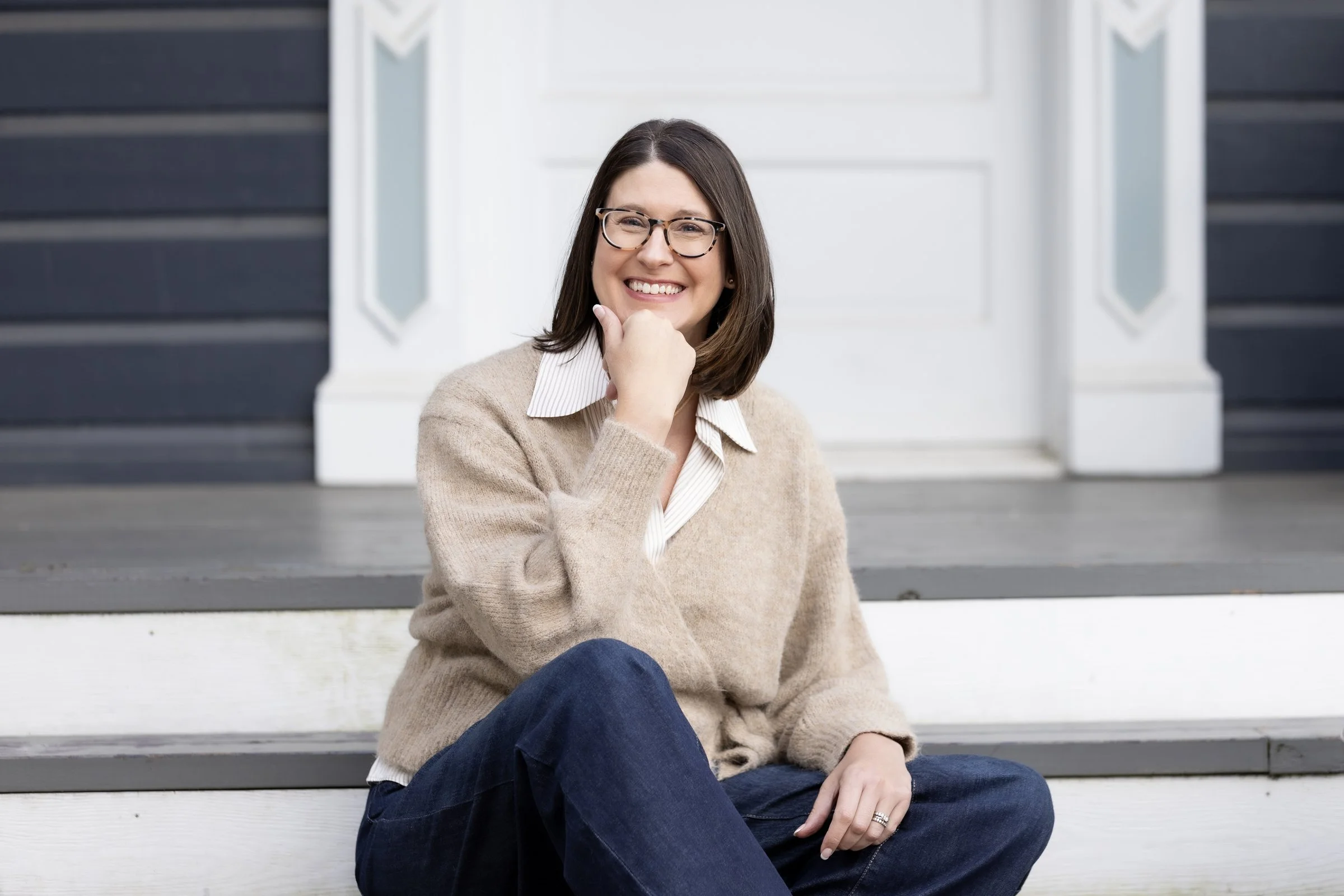 Jill Decker, LPCC, smiling on porch steps in a cream sweater