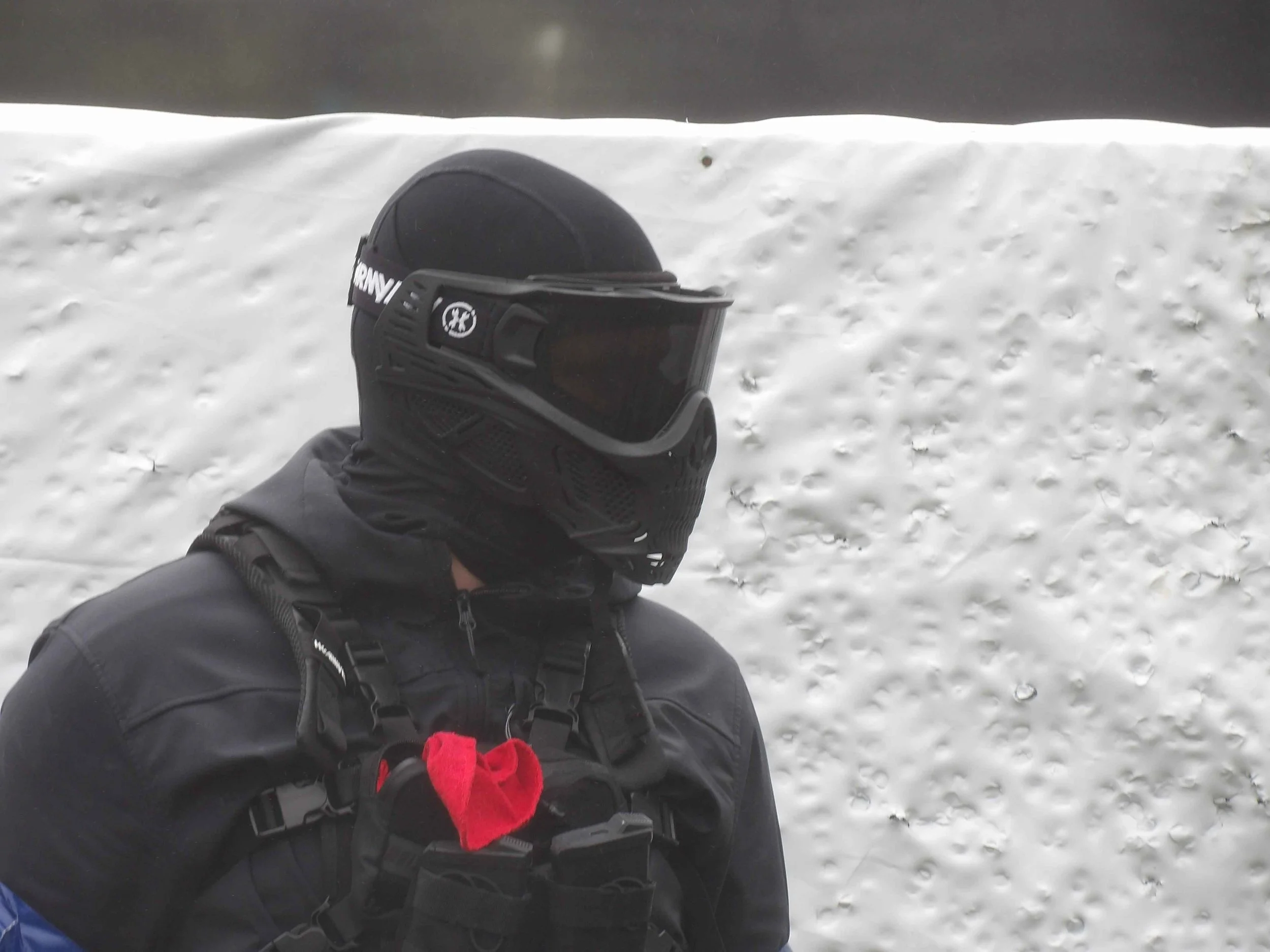 A person wearing black outdoor gear at airsoft match
