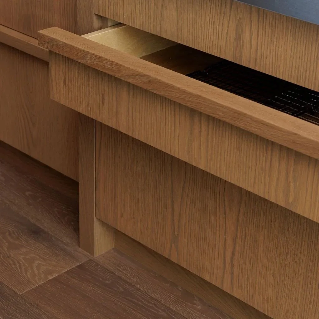 Close-up of a kitchen with wooden cabinets and a built-in Frigidaire professional oven. One of the cabinet drawers is partially pulled open, showing interior space and a wire rack.