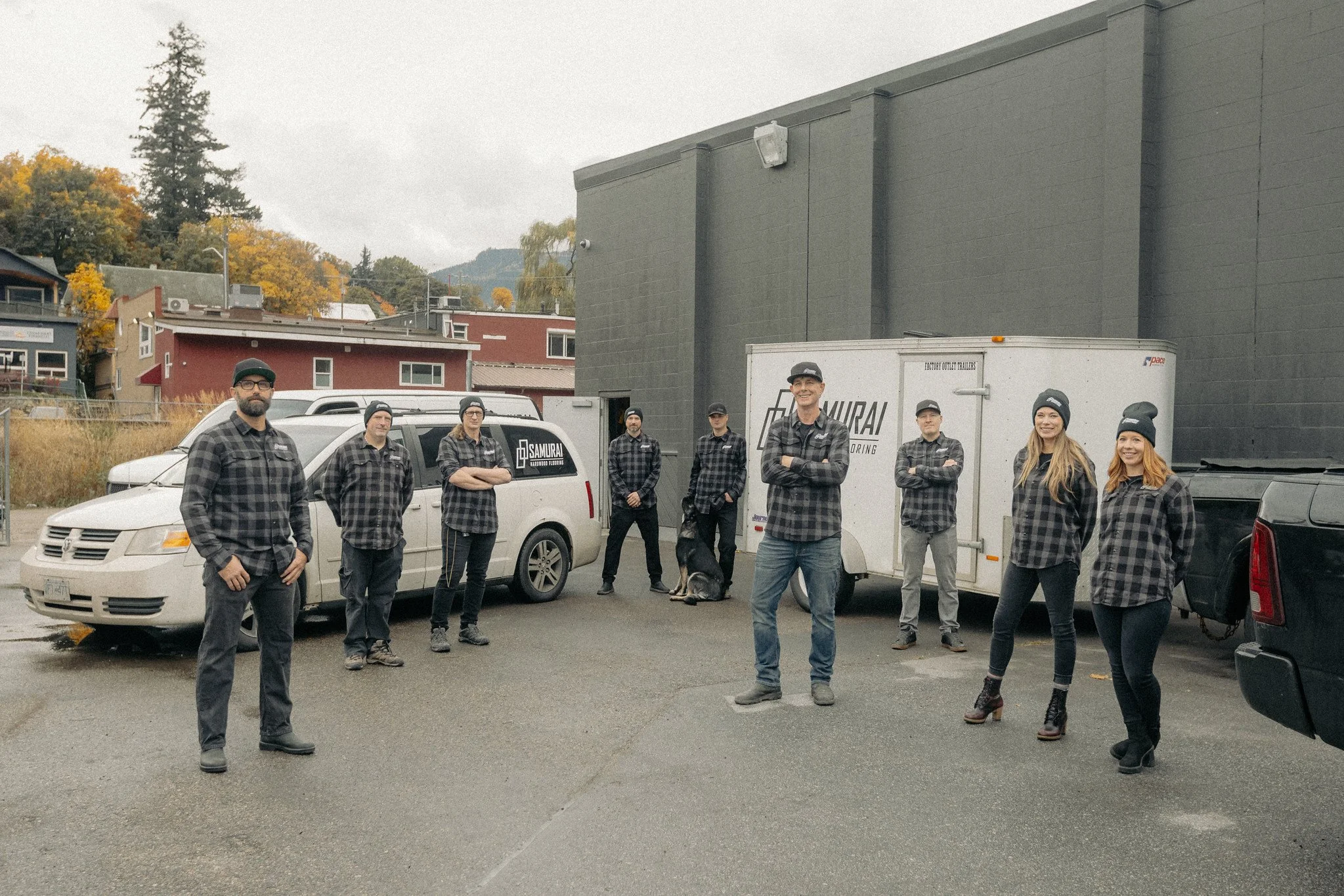 Samurai carpet cleaning team posing outside beside branded vans and a utility trailer in autumn.