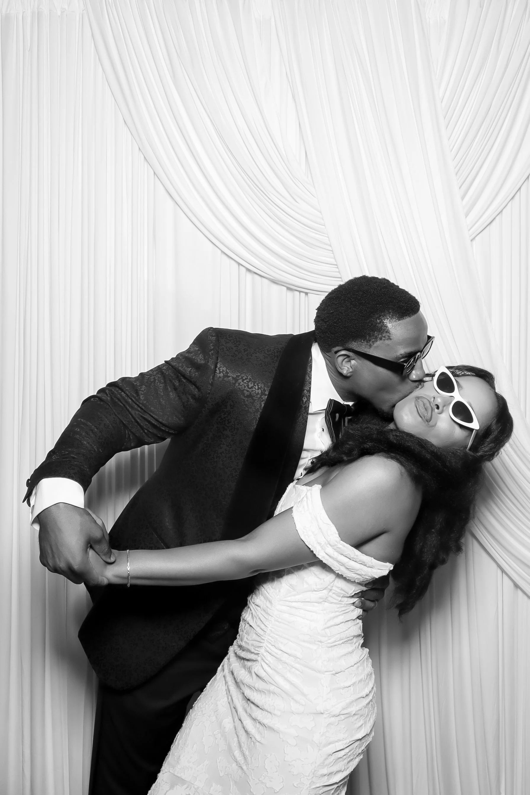Black & white couple photo
“Black and white wedding photo booth portrait of a bride and groom posing in front of an ivory drape backdrop.”
