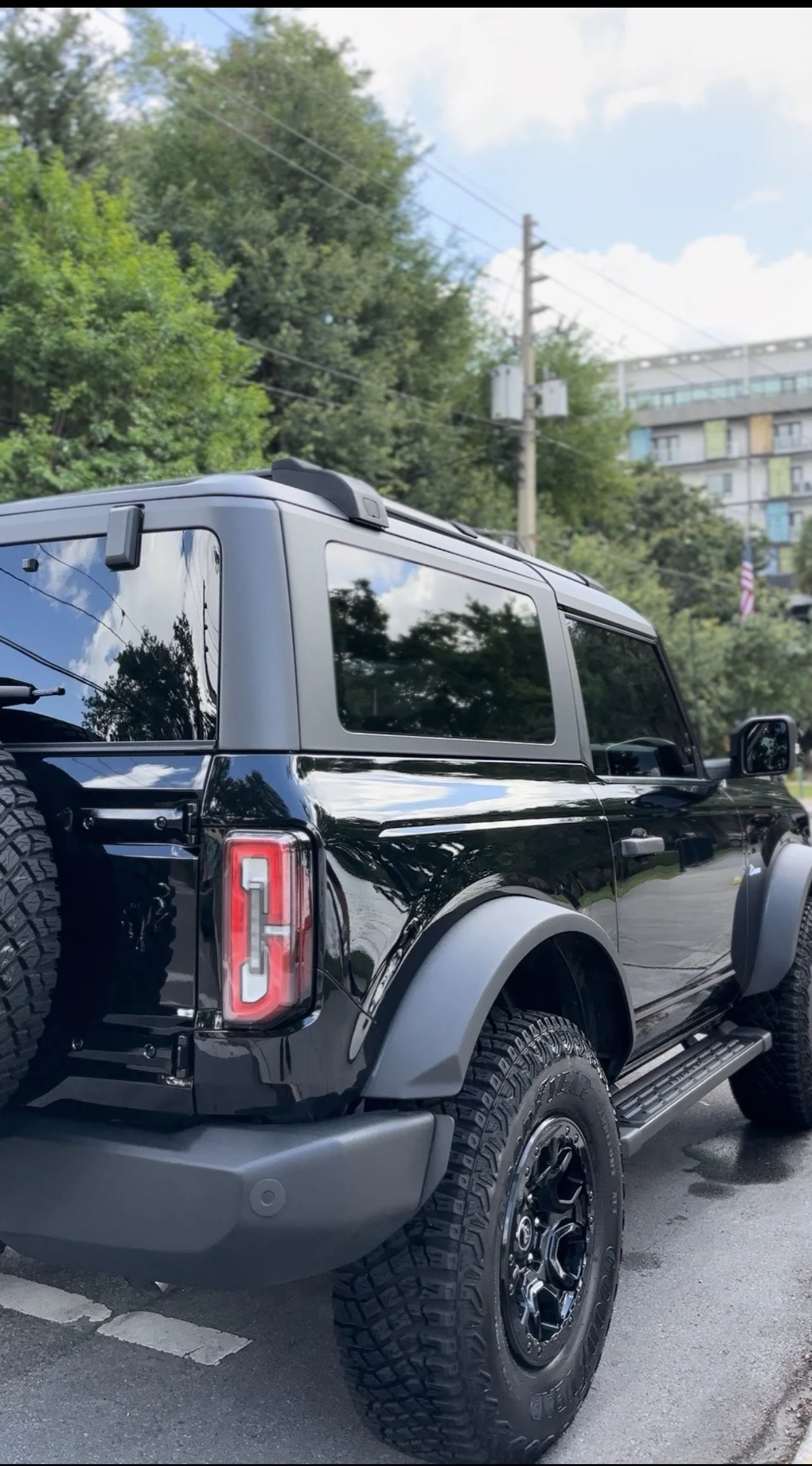 Black off-road SUV parked on the street, with trees and buildings in the background.