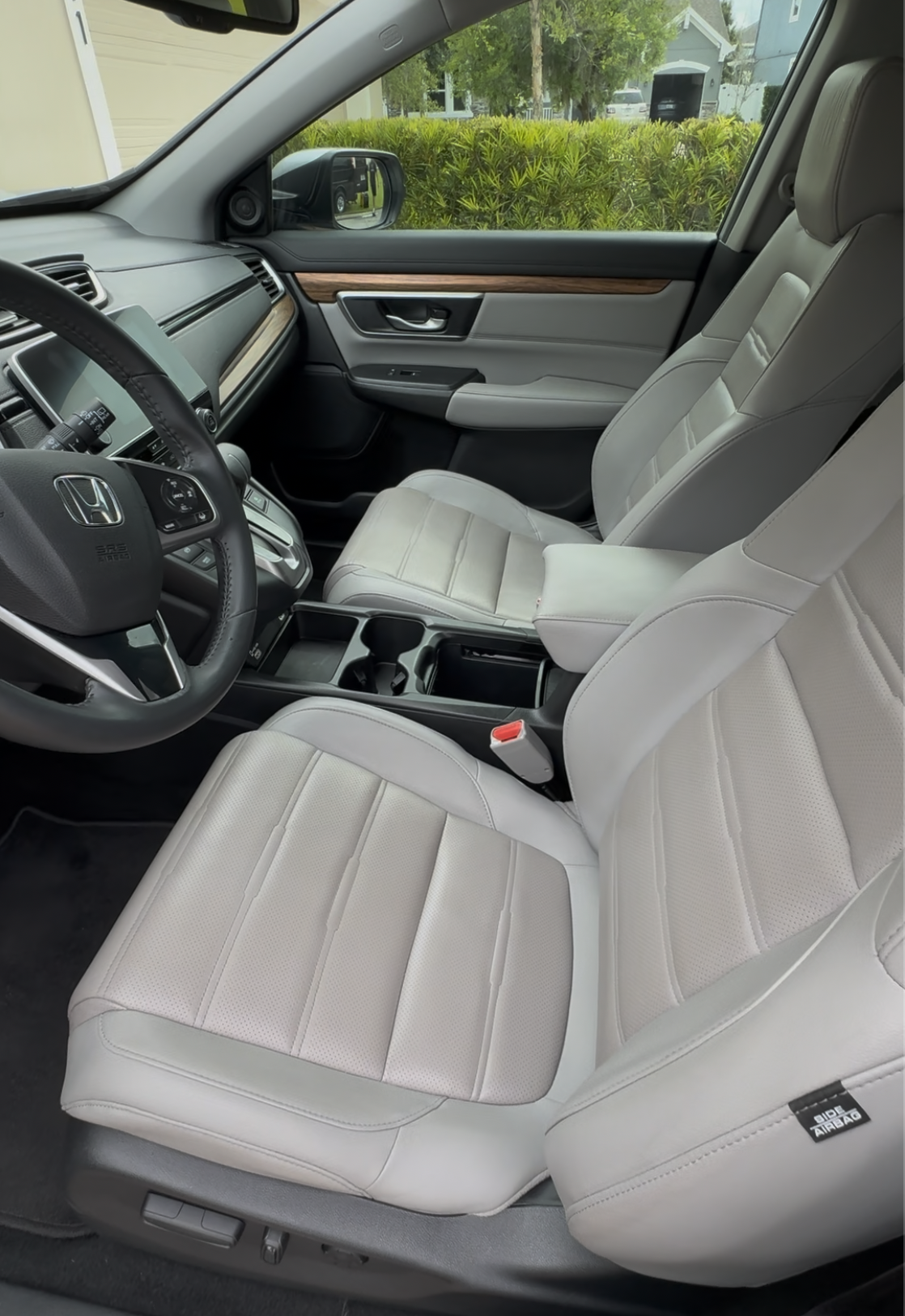 Interior of a Honda vehicle showing the front passenger and driver seats with light-colored upholstery, steering wheel, dashboard, and center console.
