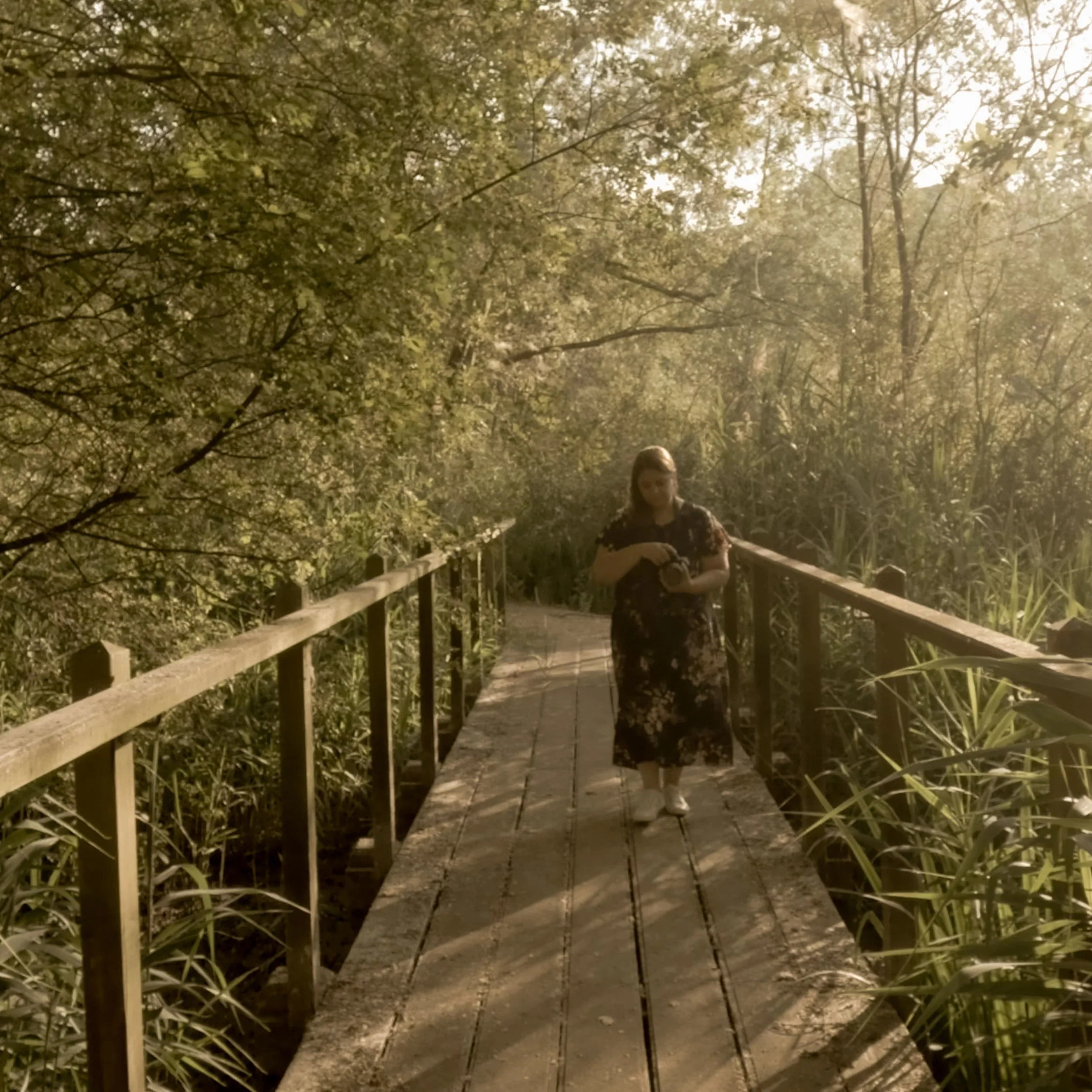 Figure walking along a misty wooden boardwalk through trees