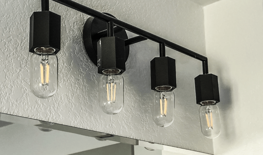 Modern four-bulb black metal ceiling light fixture with clear Edison bulbs.