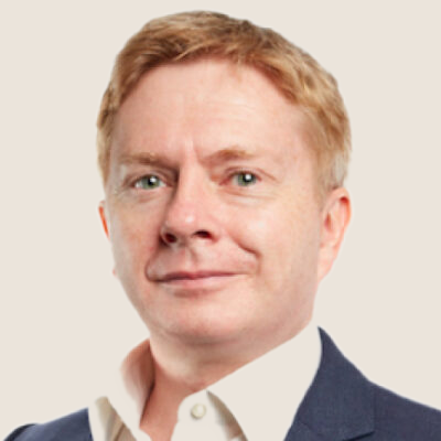 Portrait of a man with light skin, reddish hair, and wearing a white shirt and dark suit jacket.