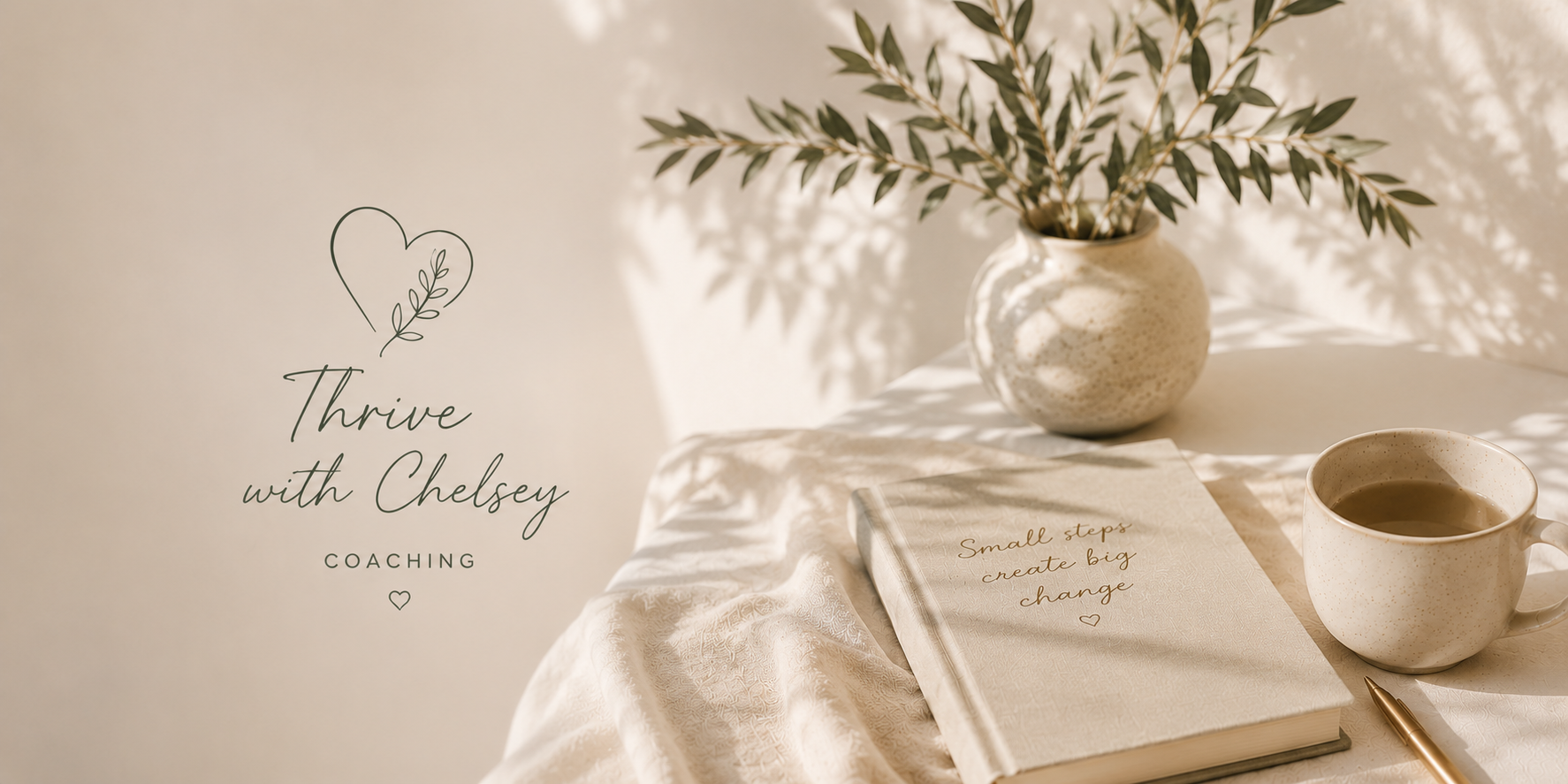 A cozy workspace with a white tablecloth, a beige ceramic vase with green leafy branches, a closed notebook with a quote, a ceramic cup of tea, and a gold pen, set against a light-colored wall decorated with a hand-drawn heart and leaf illustration with the text "Thrive with Chelsey Coaching" and a small heart.
