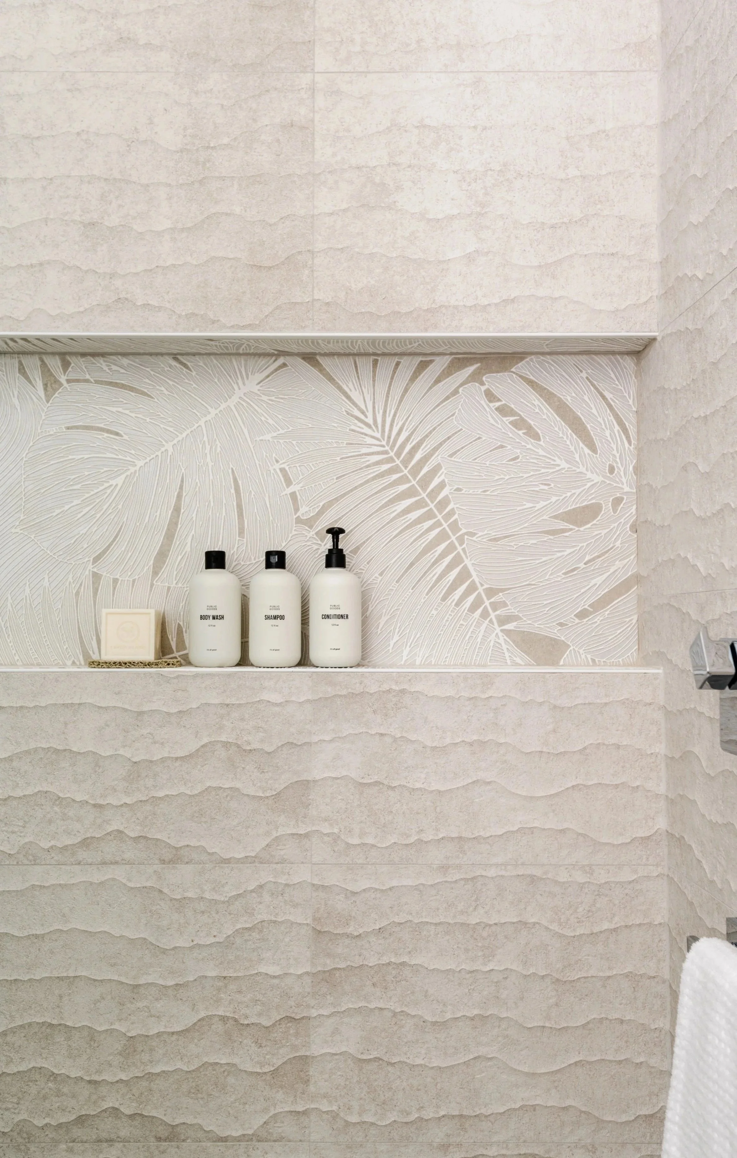 A photo of a shower with tan tiles that have organic textures with "Tile Envy" text overlay