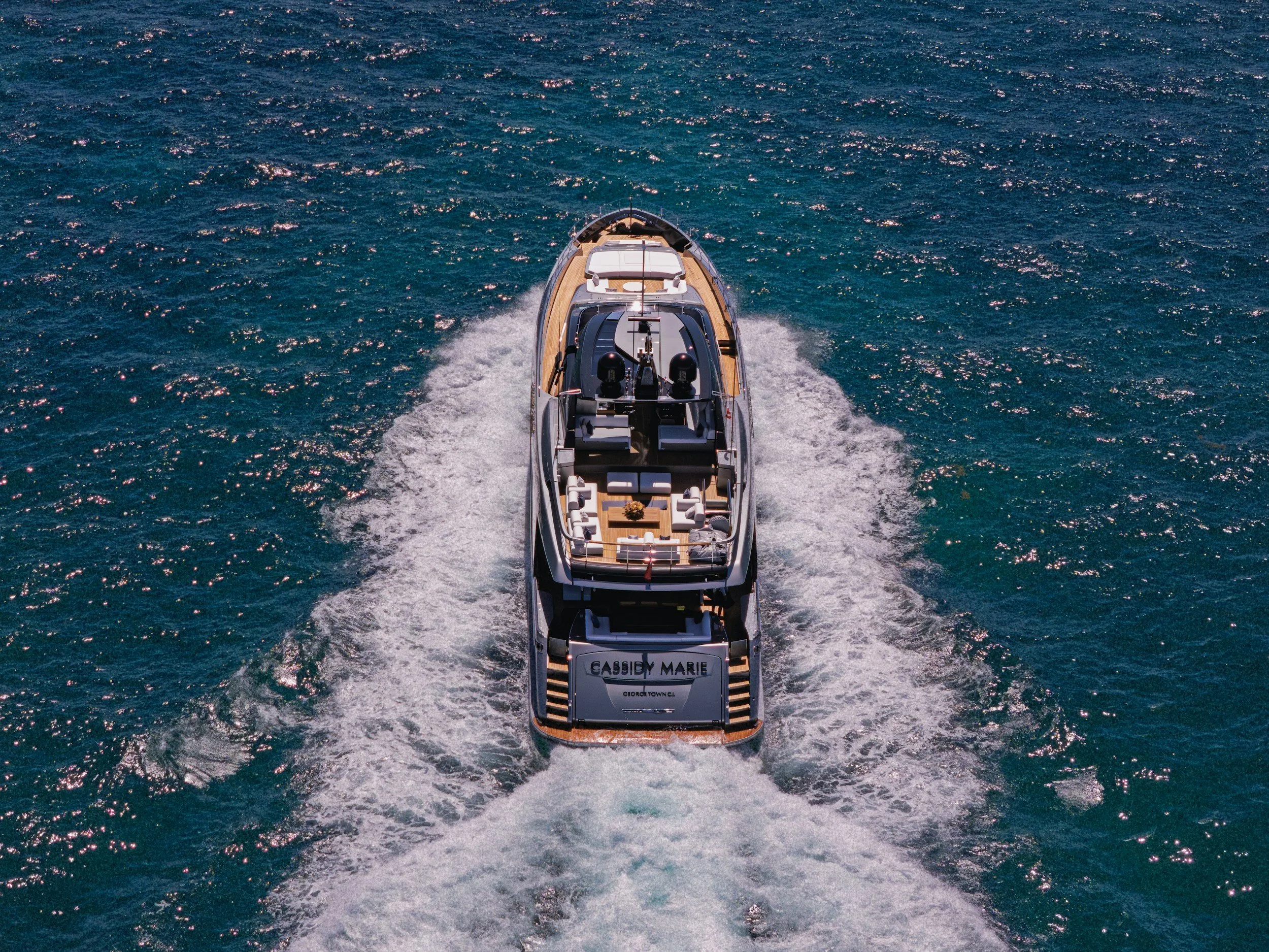 A yacht named Cassidy Marie moving through the ocean, creating a wake behind it with sparkling blue water.