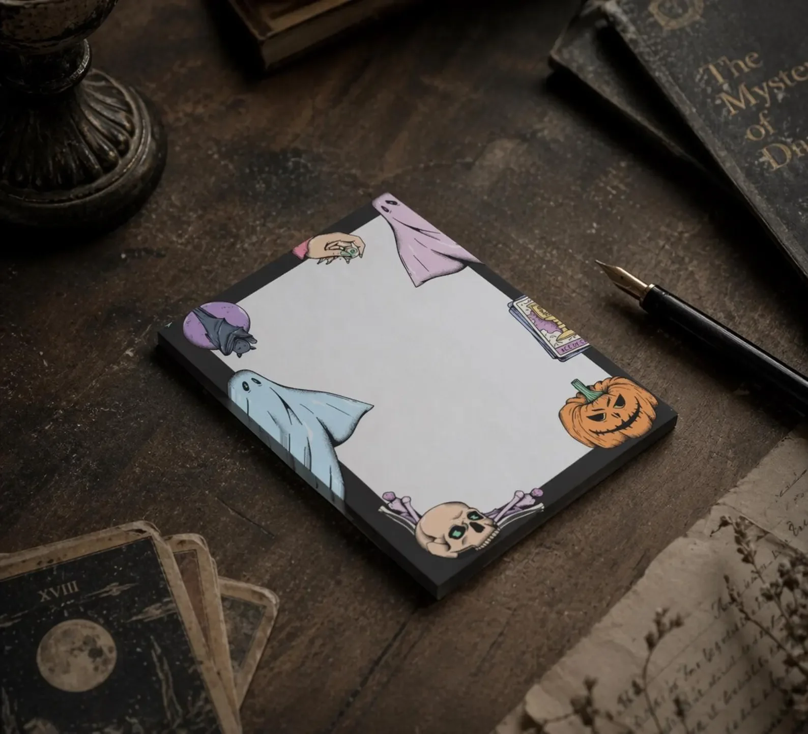 A notebook with cartoon Halloween-themed illustrations, including a ghost, skull, pumpkin, and bat