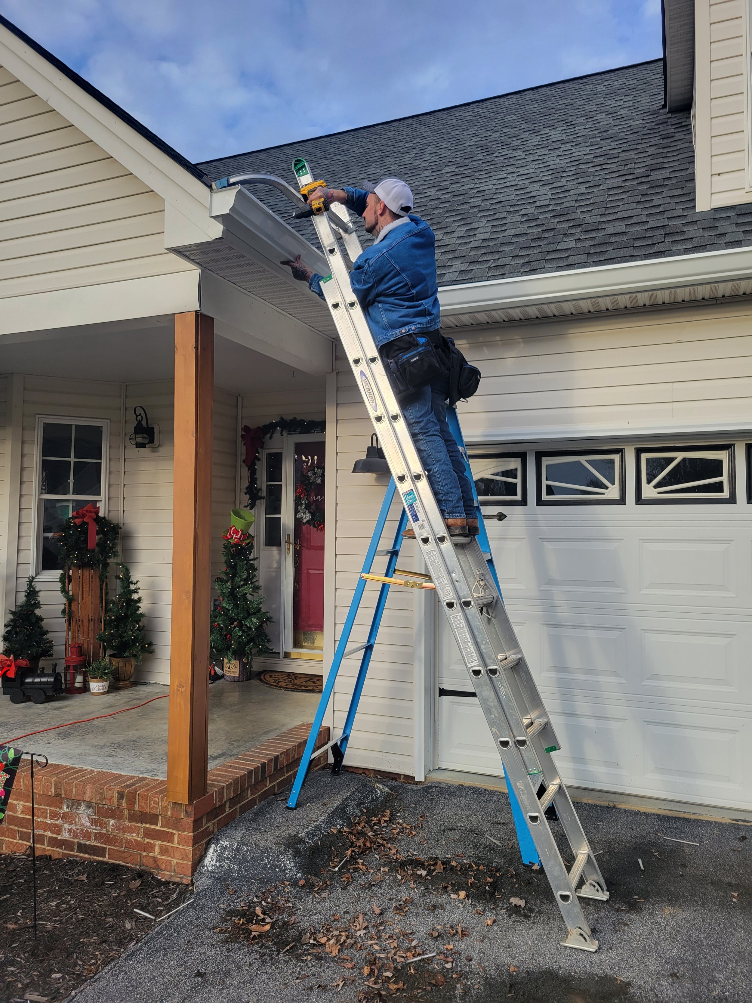 Armor Exteriors technician working from a ladder at the roof and gutter edge of a residential home in Upstate South Carolina.