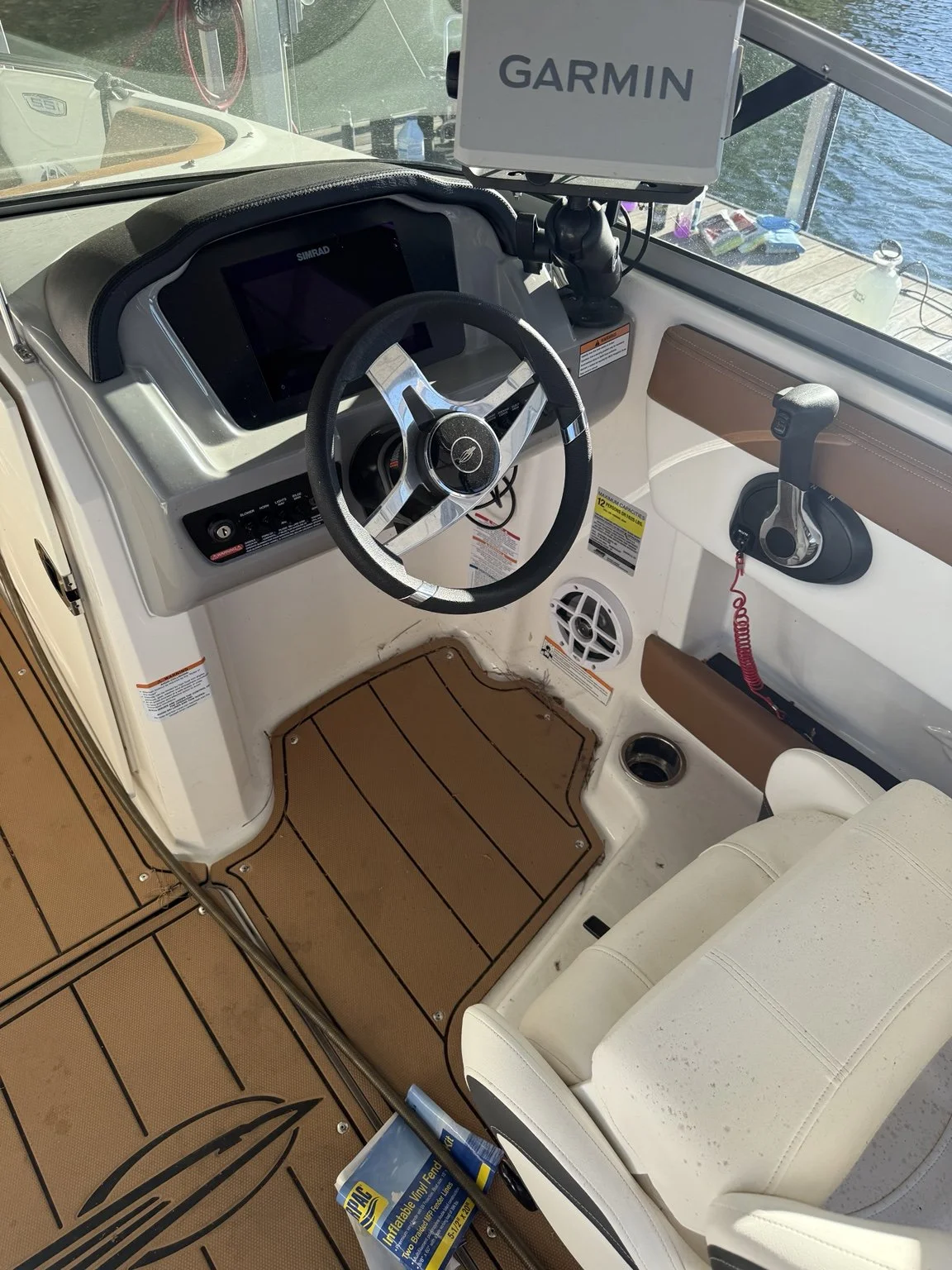 Helm detail: steering wheel, instruments and tan fitted floor panels beside white seating.