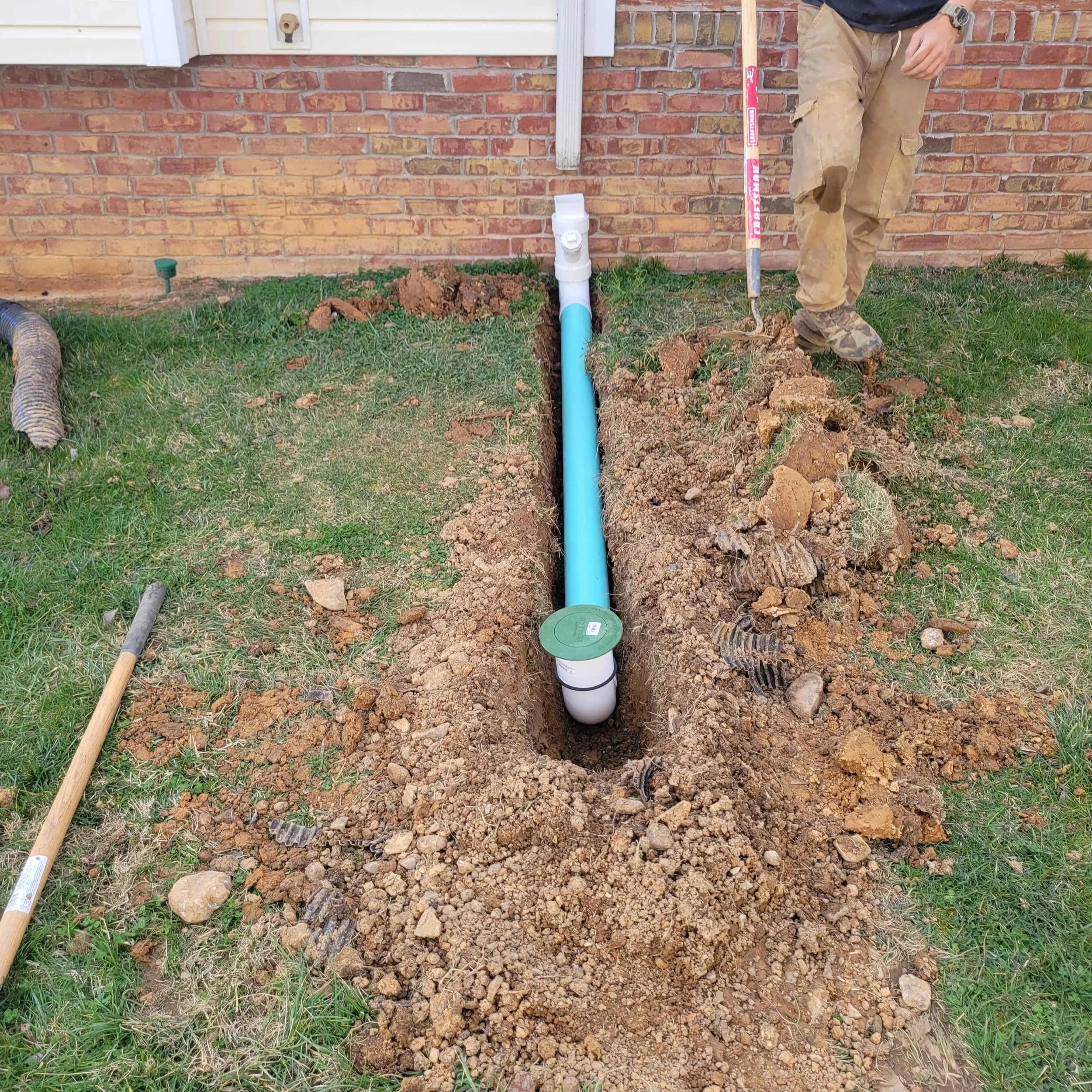 Armor Exteriors technician installing an underground drainage pipe beside a home in Lake Keowee, South Carolina.