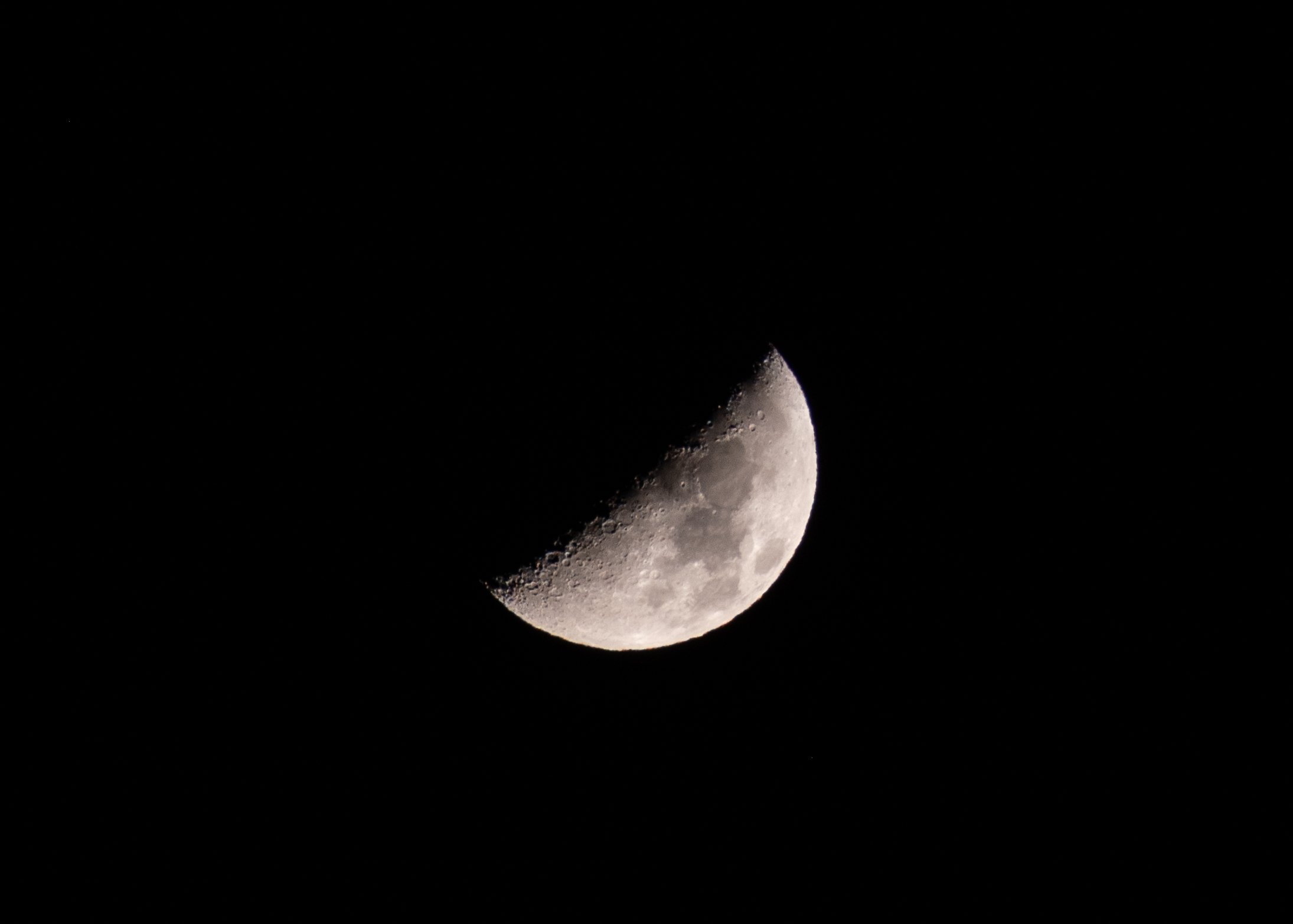 A close-up photograph of the moon showing its craters and surface details against a black night sky.