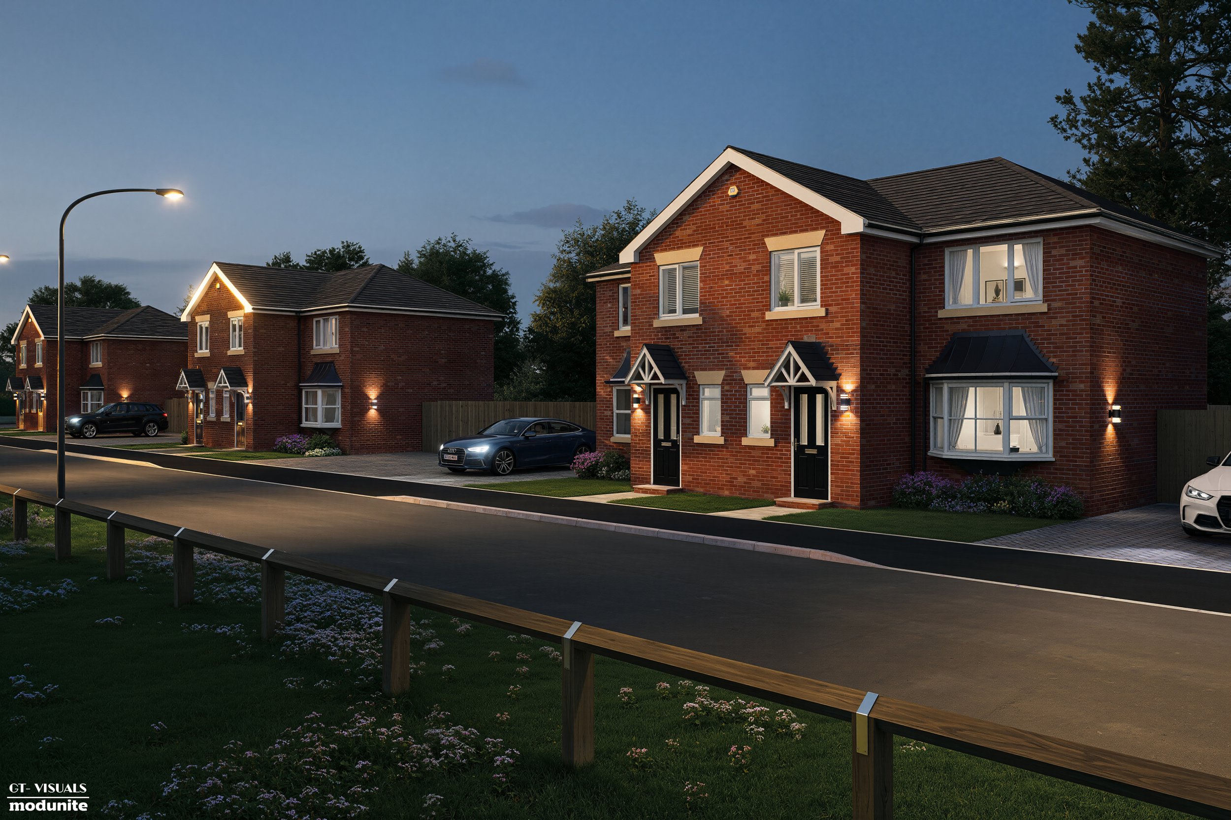 A row of modern brick houses illuminated at dusk with cars parked in front and a streetlight on the left side of the street.