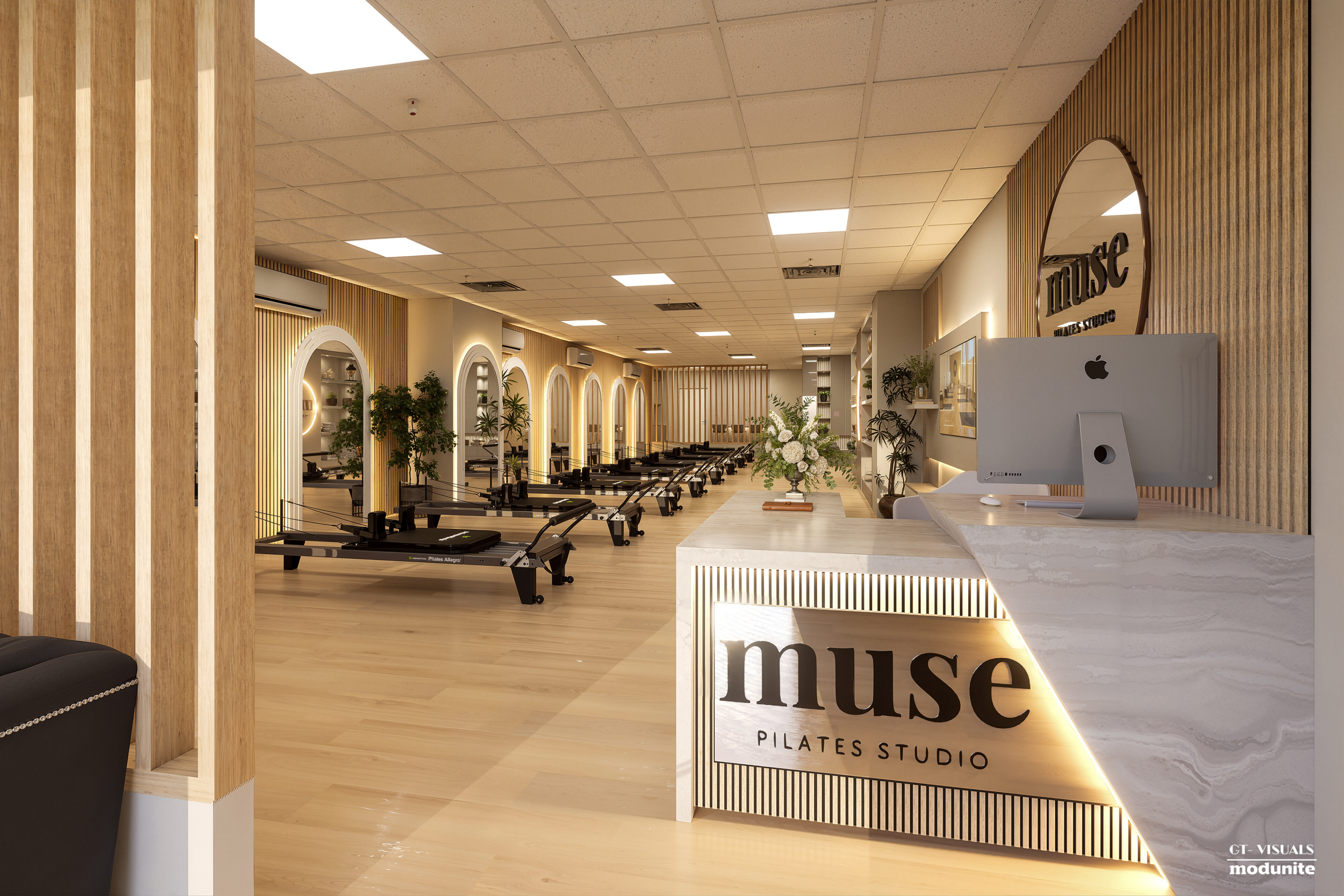 Interior view of the Muse Pilates Studio with wooden accents, Pilates reformer machines, and a reception desk with the studio's name.
