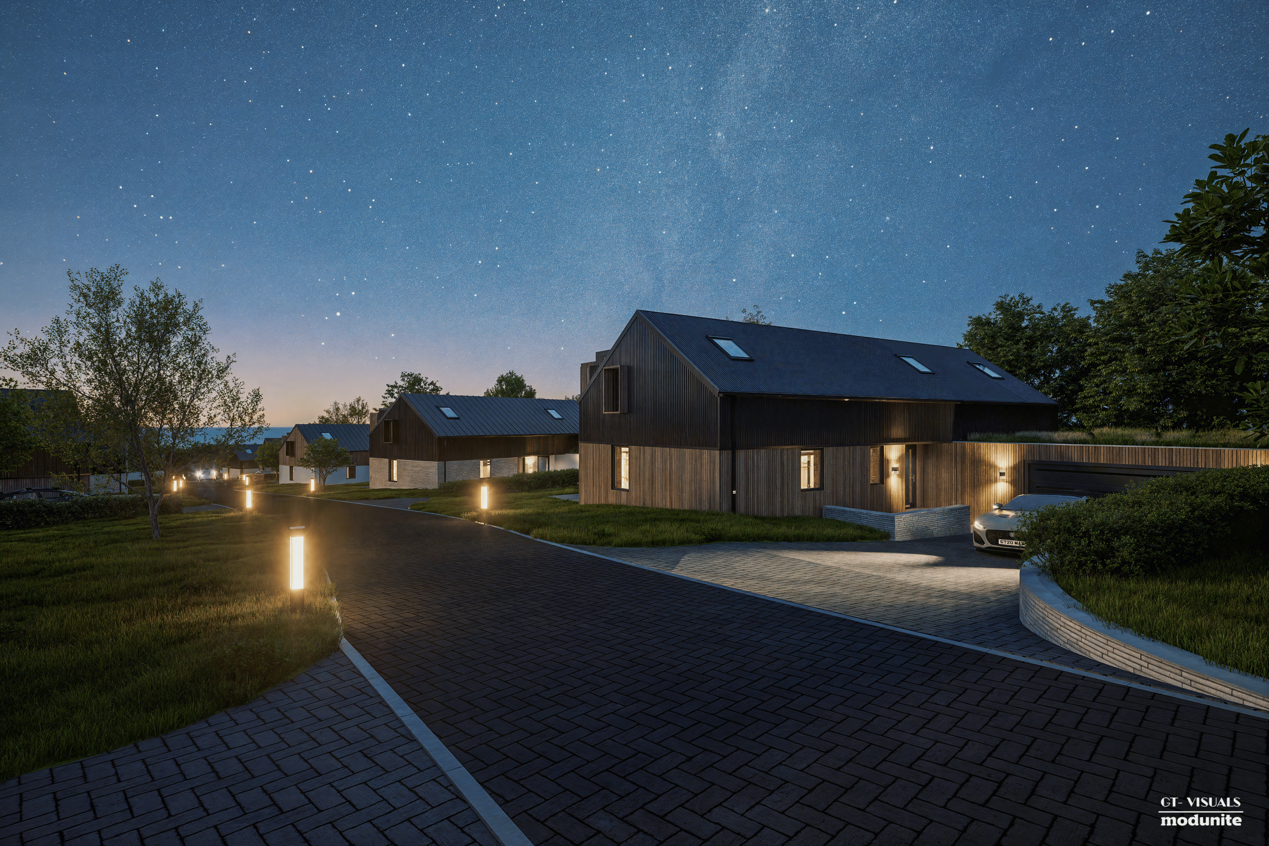 Nighttime view of modern houses with sloped roofs and large windows, illuminated by pathway lights, under a starry sky with many visible stars.