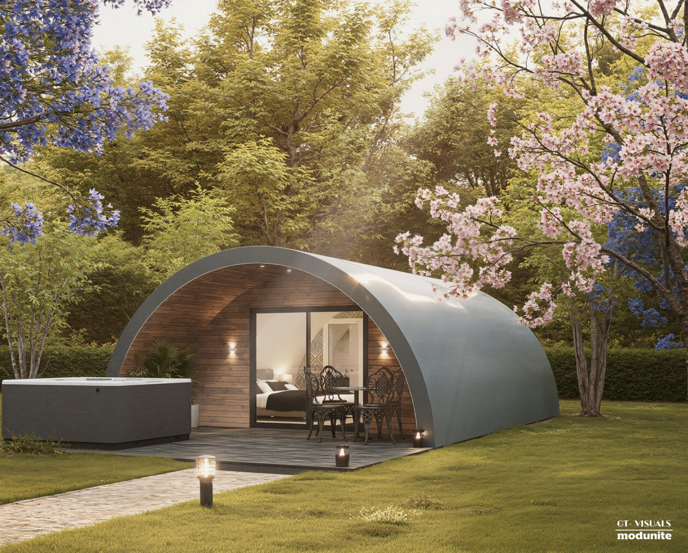 Modern, curved outdoor metal structure with wood interior, open on one side, surrounded by trees with pink and purple flowers, lit with outdoor lights and lanterns, with a brick pathway in front.