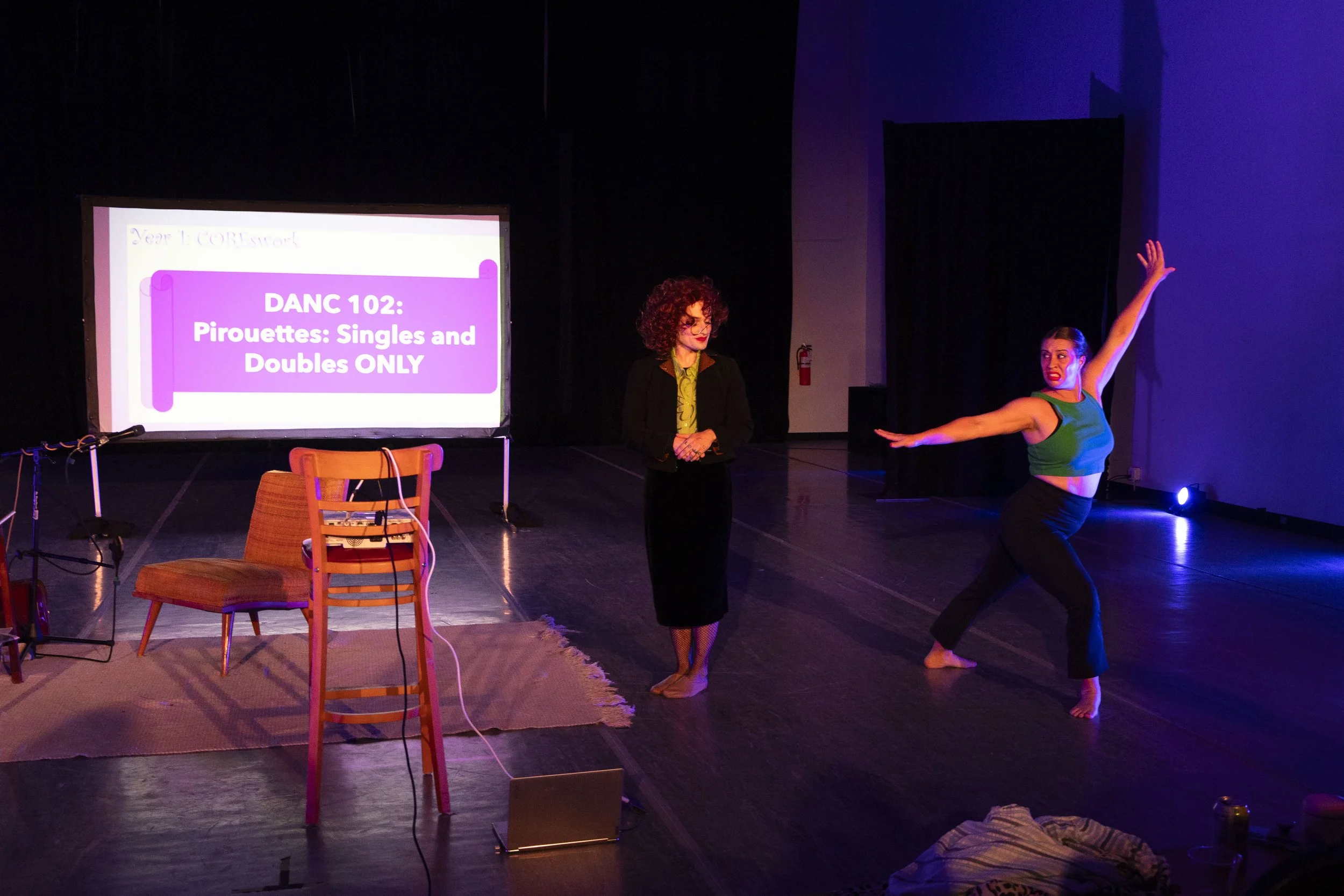 Miss Vikki looks on, judging, as Amy lands a pirouette. Amy looks nervous.