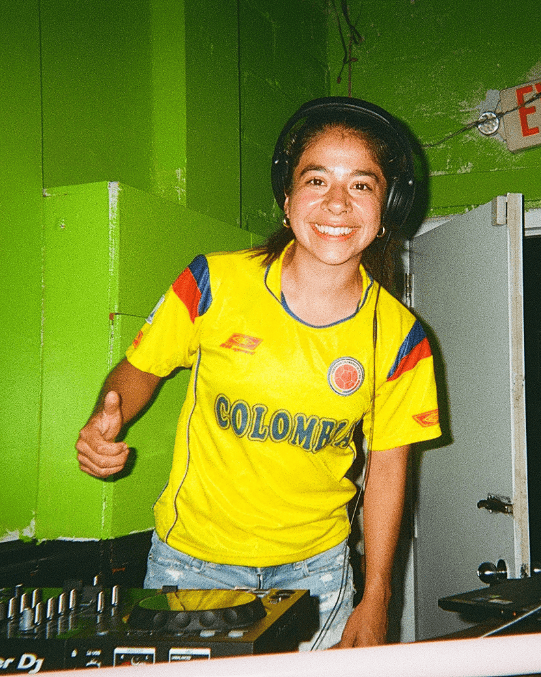 DJ Bala, Jessie Gomez, smiling and giving a thumbs-up while standing behind DJ equipment at Lolo's Social Club.