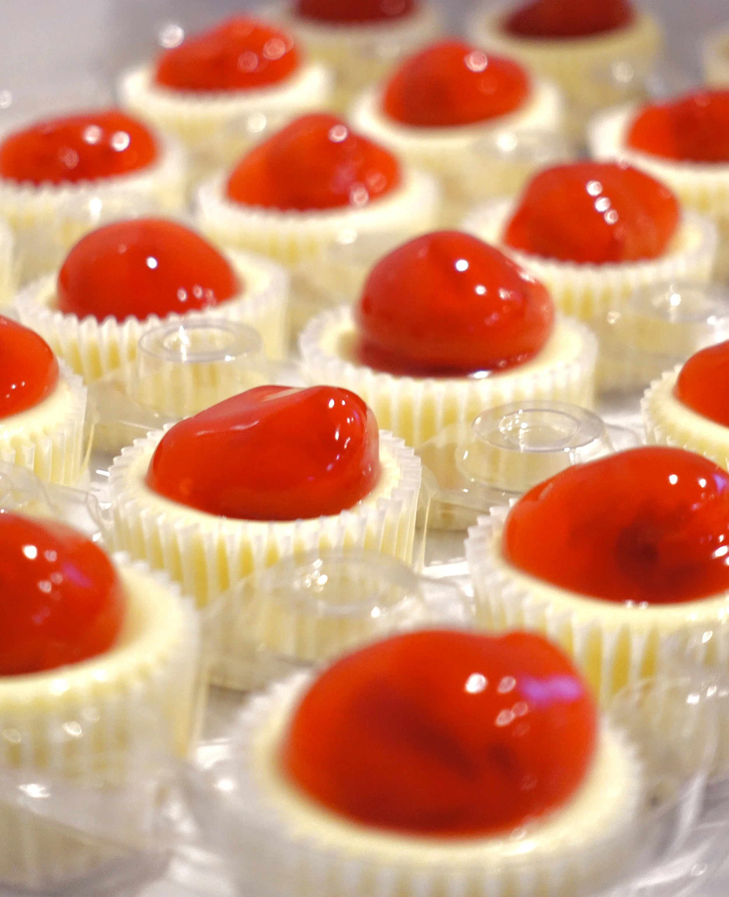 Mini cupcakes with white frosting topped with red jelly or fruit