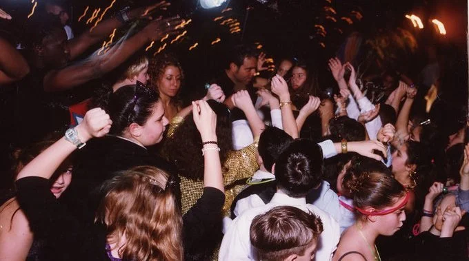 Crowd of young people dancing to a DJ at a party or Bar or Bat Mitzvah with colorful lighting.
