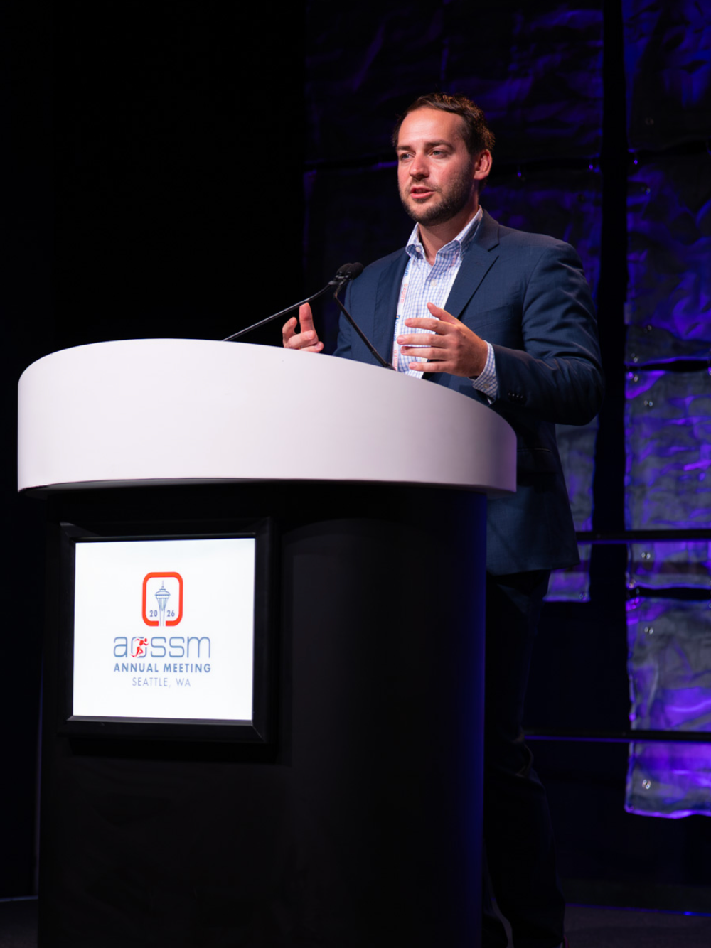 Dr. Joshua Eskew speaking at a podium during the ARSSM Annual Meeting in Seattle, WA, 2026.