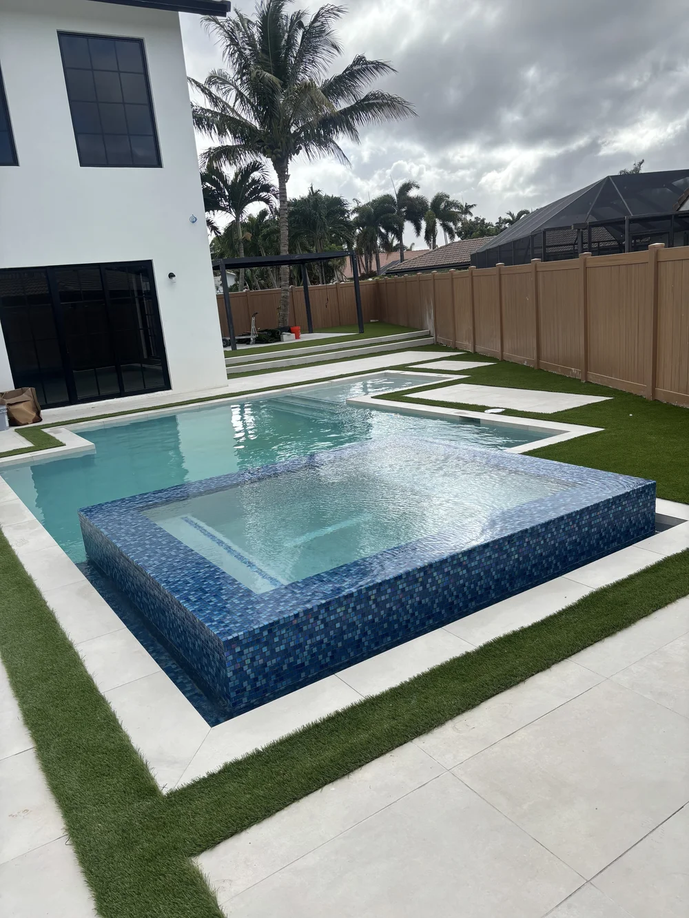 Raised spa with glass mosaic tile inside a pool