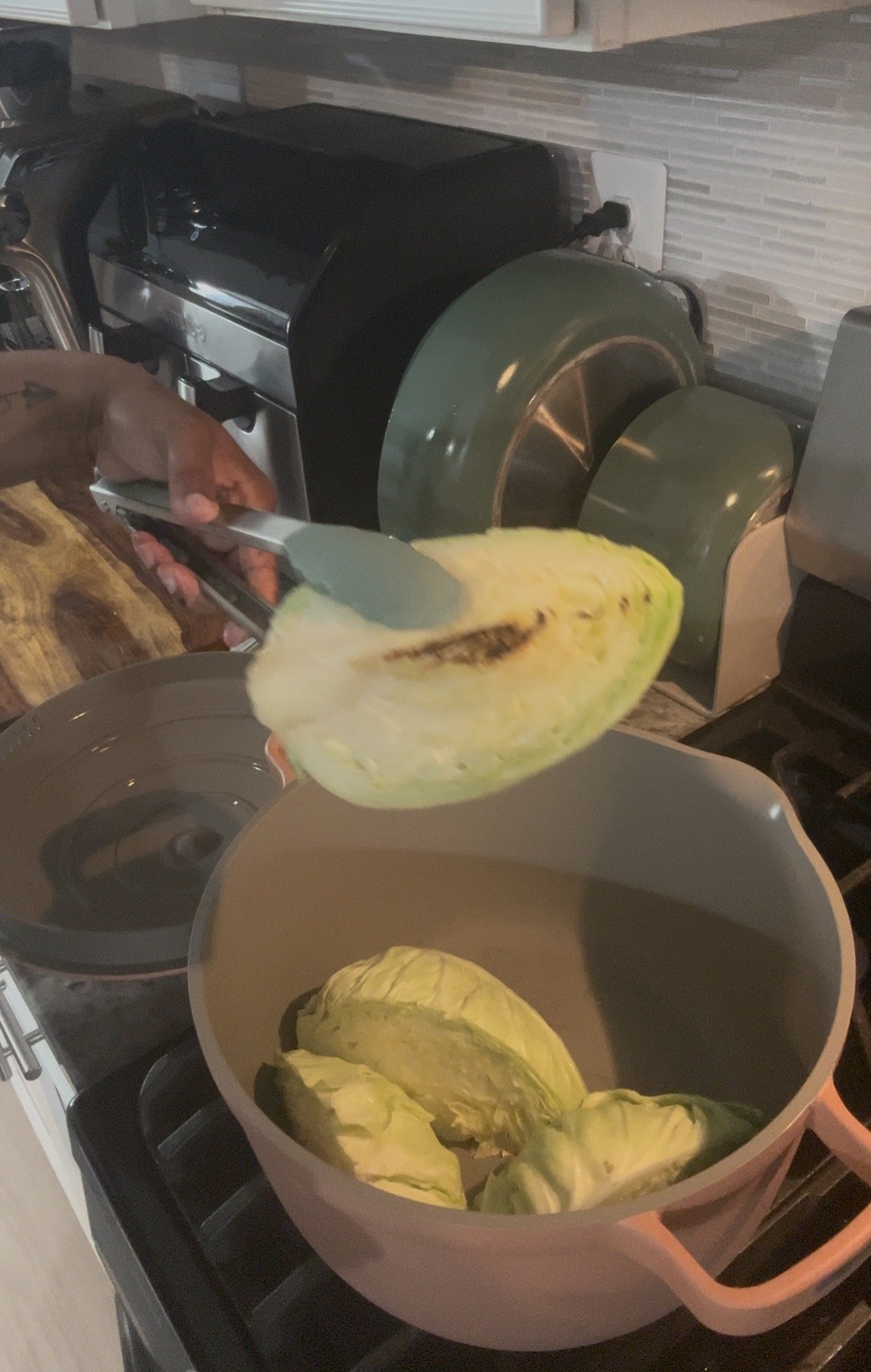 A person grilling slices of pineapple on a barbecue grill in a kitchen.