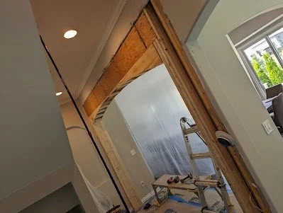 Interior of a house under renovation with drywall installation and a stepladder.