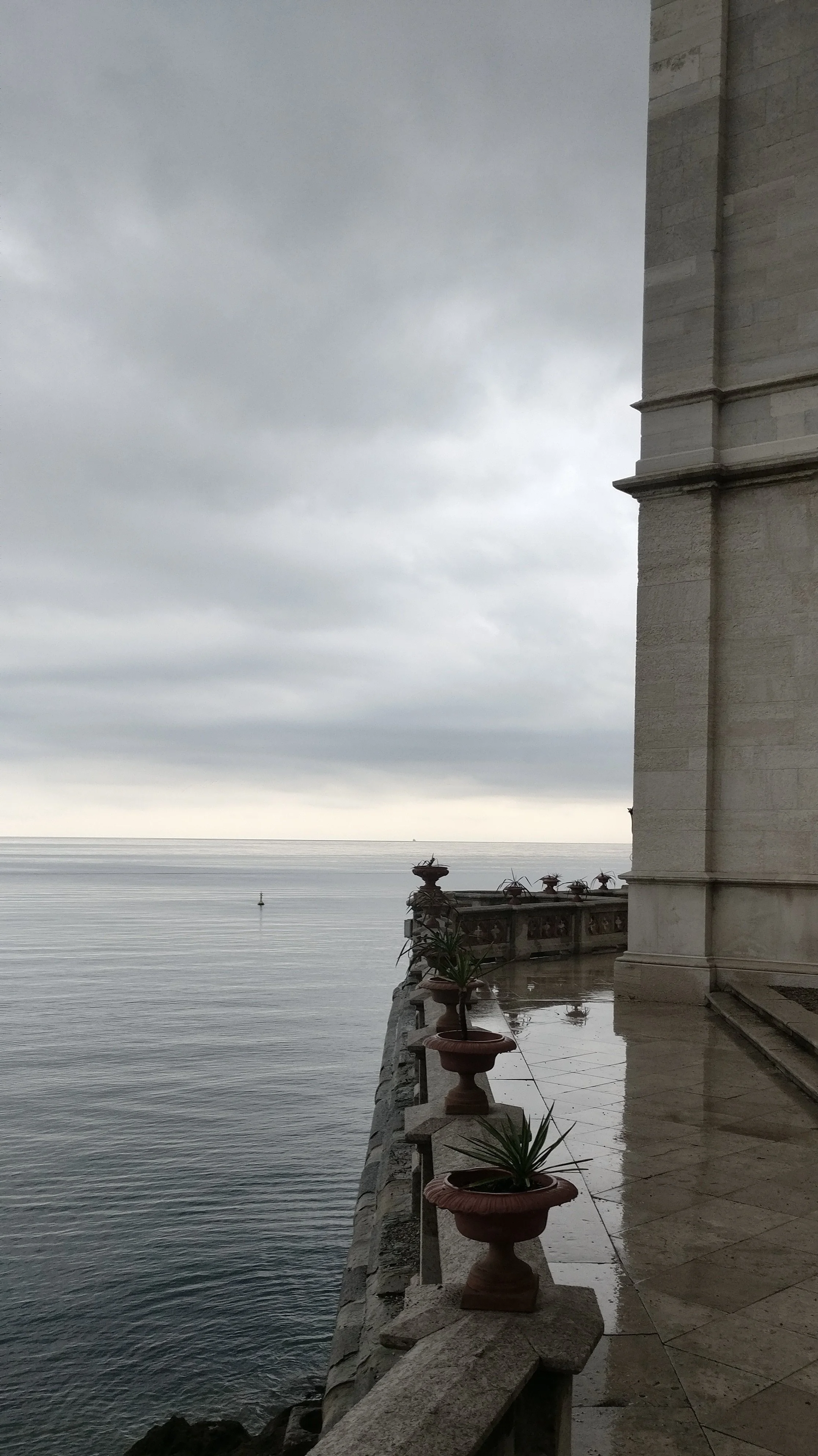 A quiet, reflective stone terrace next to a vast, calm sea under an overcast sky, illustrating the safe space and mental clarity achieved through psychotherapy.