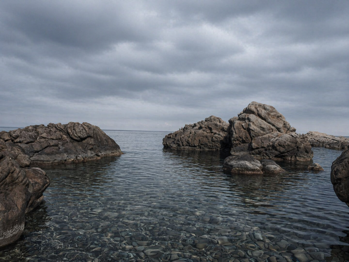 A peaceful, protected rocky cove with crystal-clear, still water, symbolizing the grounding, stabilizing, and nervous-system-regulating effects of slow-paced breathwork.