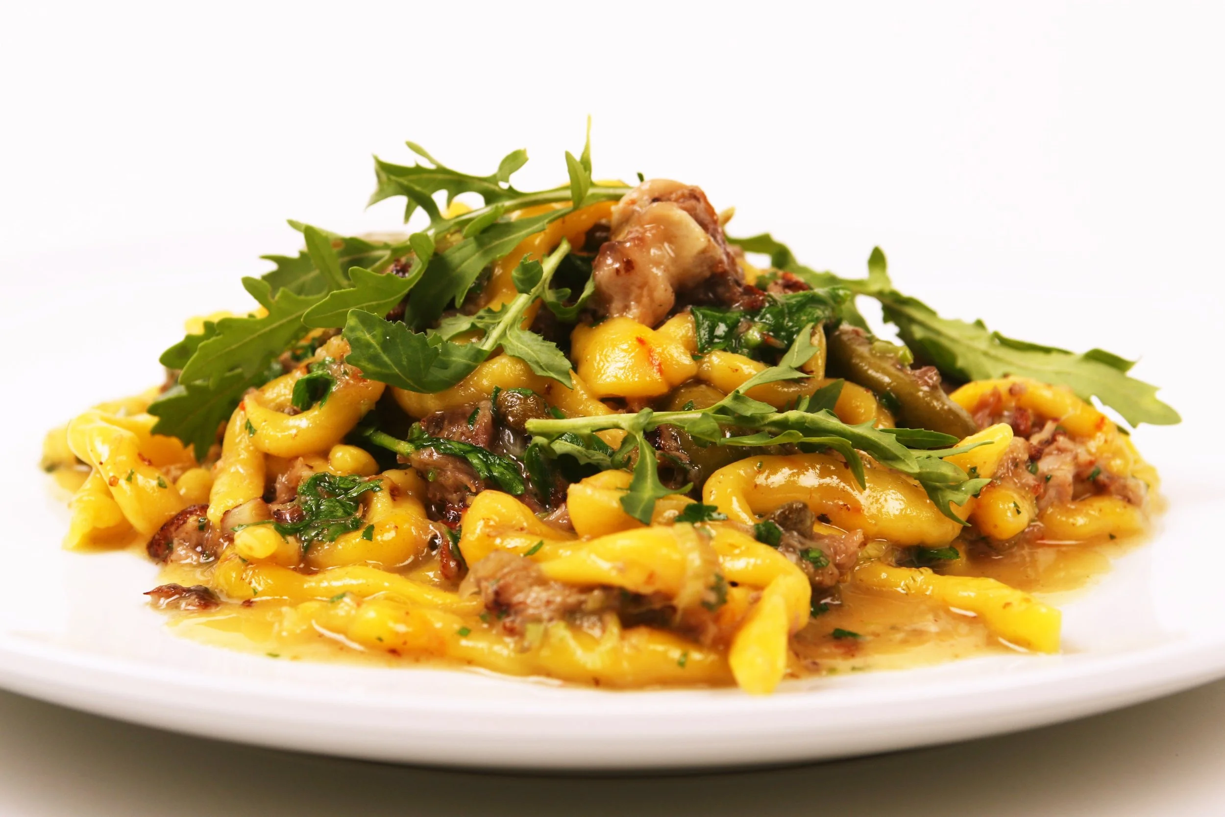 Strozzapreti with Pork Cheek Ragù, Cerignola Olives, and Wilted Arugula. 