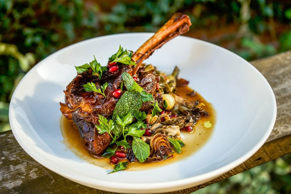 Braised Lamb Shank, Long-Cooked Greens, Sauteed Mushrooms, Soft Herbs, and Pomegranate.  