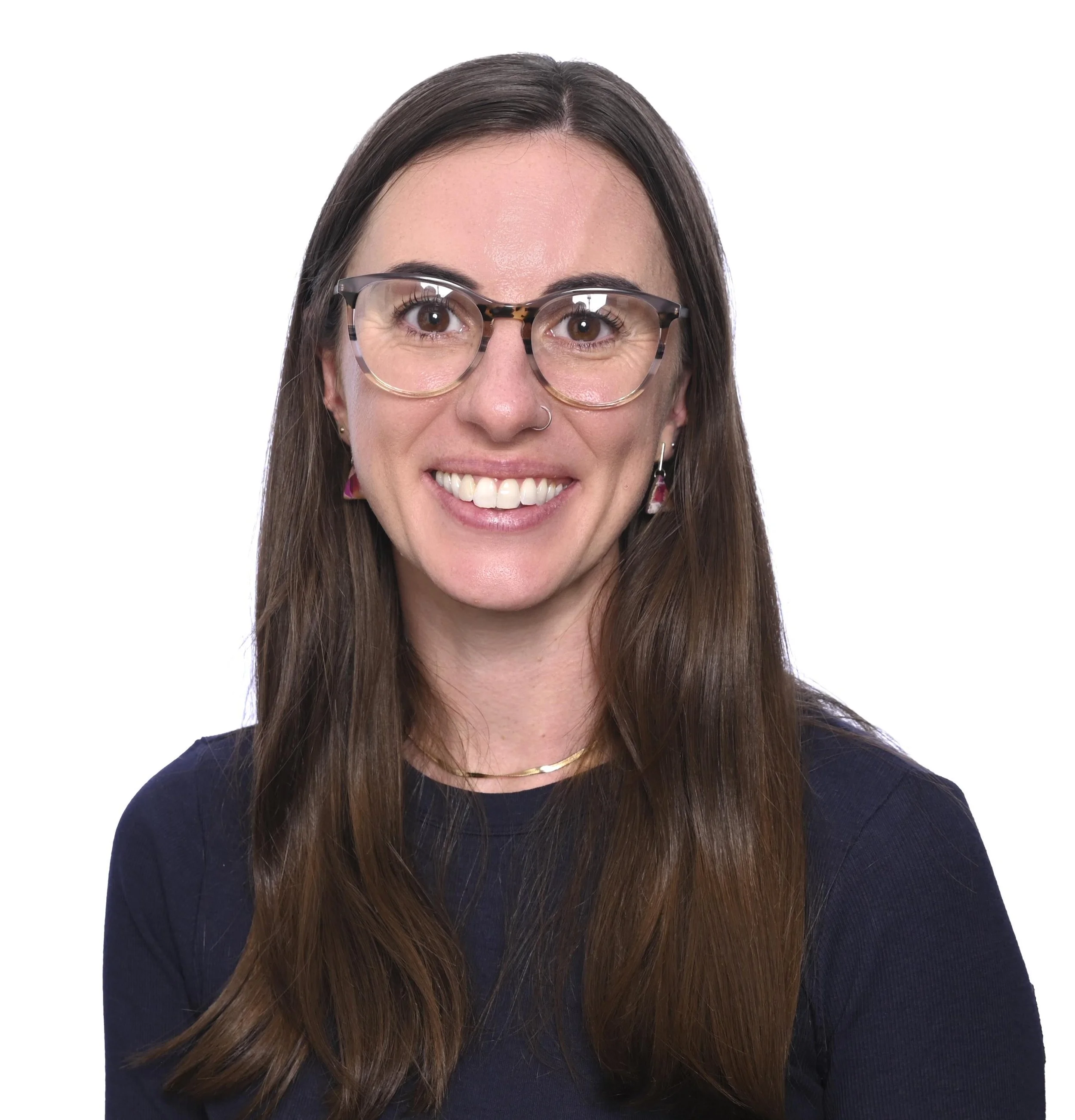 Close-up of a woman with long brown hair and glasses, smiling, against a white background.