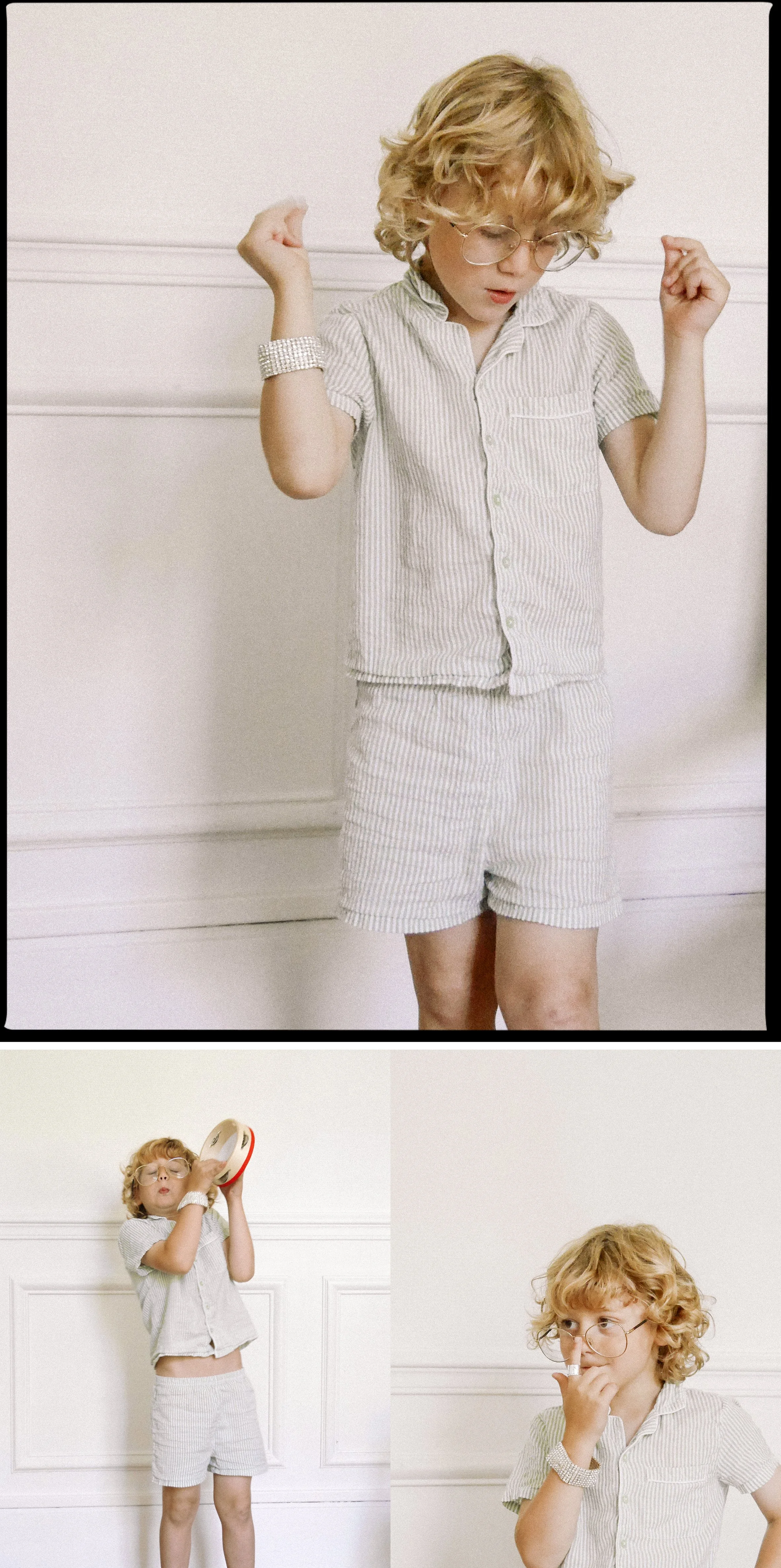Une jeune fille blond aux cheveux bouclés, portant des vêtements à rayures, porte des lunettes et un bracelet brillant, elle pose dans une pièce aux murs blancs. Elle fait différentes expressions et gestes, notamment en levant les bras et en se tenant le nez.