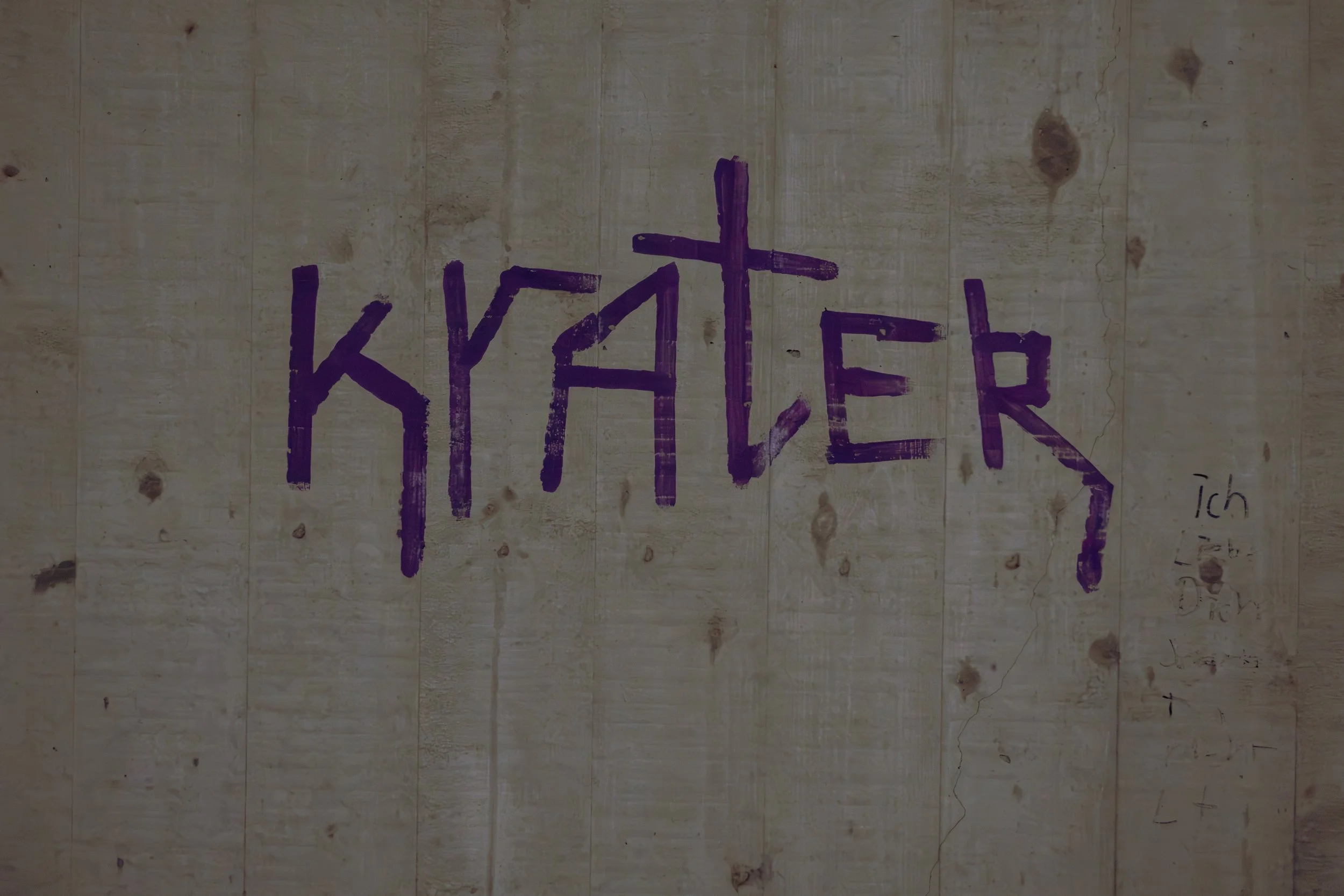 Wand mit handgeschriebenem Satz in violetter Farbe, der „K Y F E R“ schreibt.