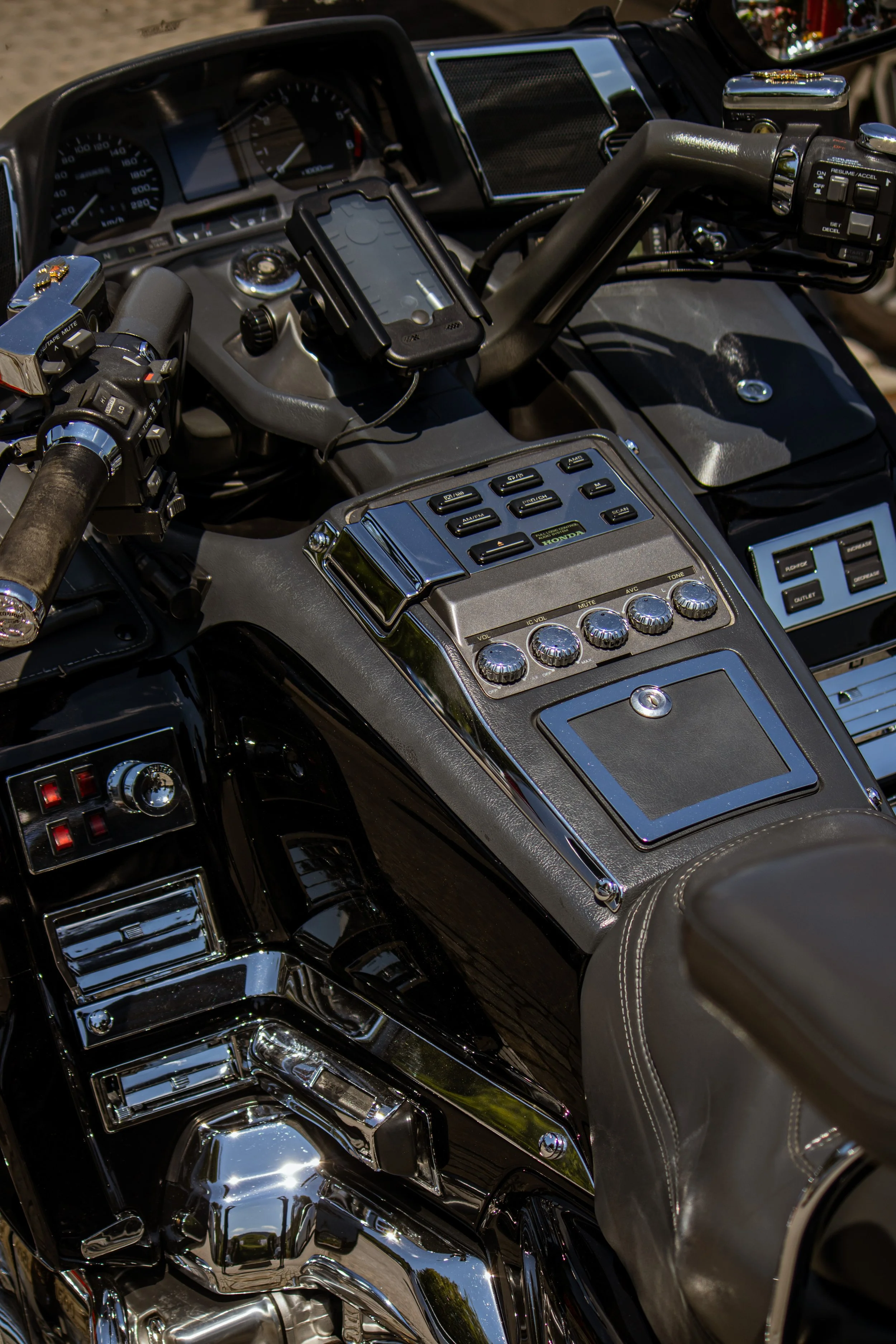 Ein Motorrad mit einem Dashboard und zahlreichen Steuerungen, einem Handyhalter, mechanischen Teilen, Knöpfen, Schaltern und reflektierenden Flächen.