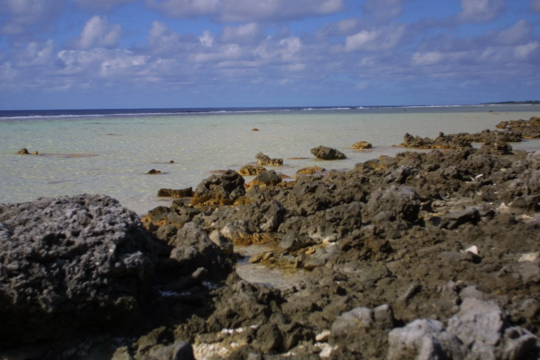 Rocky shoreline with ocean and cloudy sky in the background.