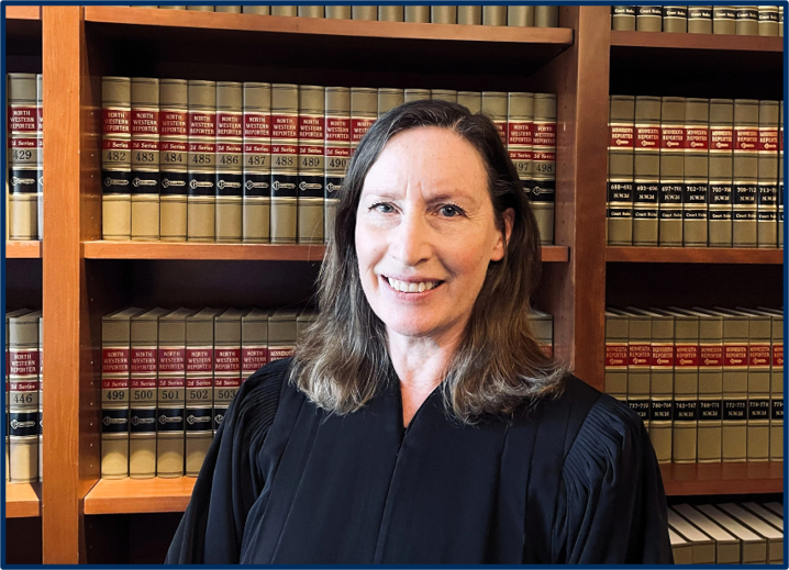 Woman in judge robes in front of books.