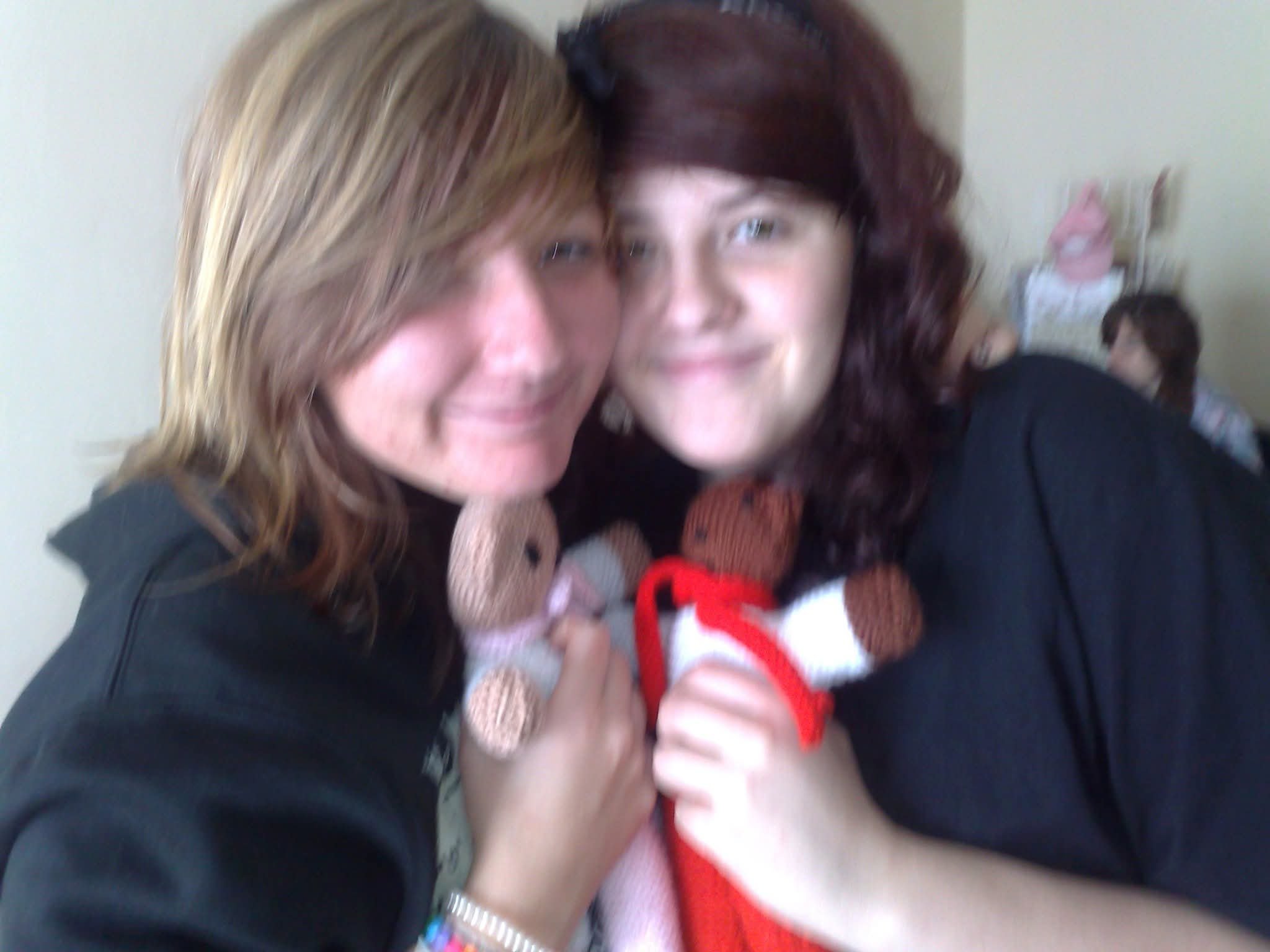 A woman with wavy brown hair and fair complexion smiling, close to a young girl with straight brown hair and fair complexion, indoors.