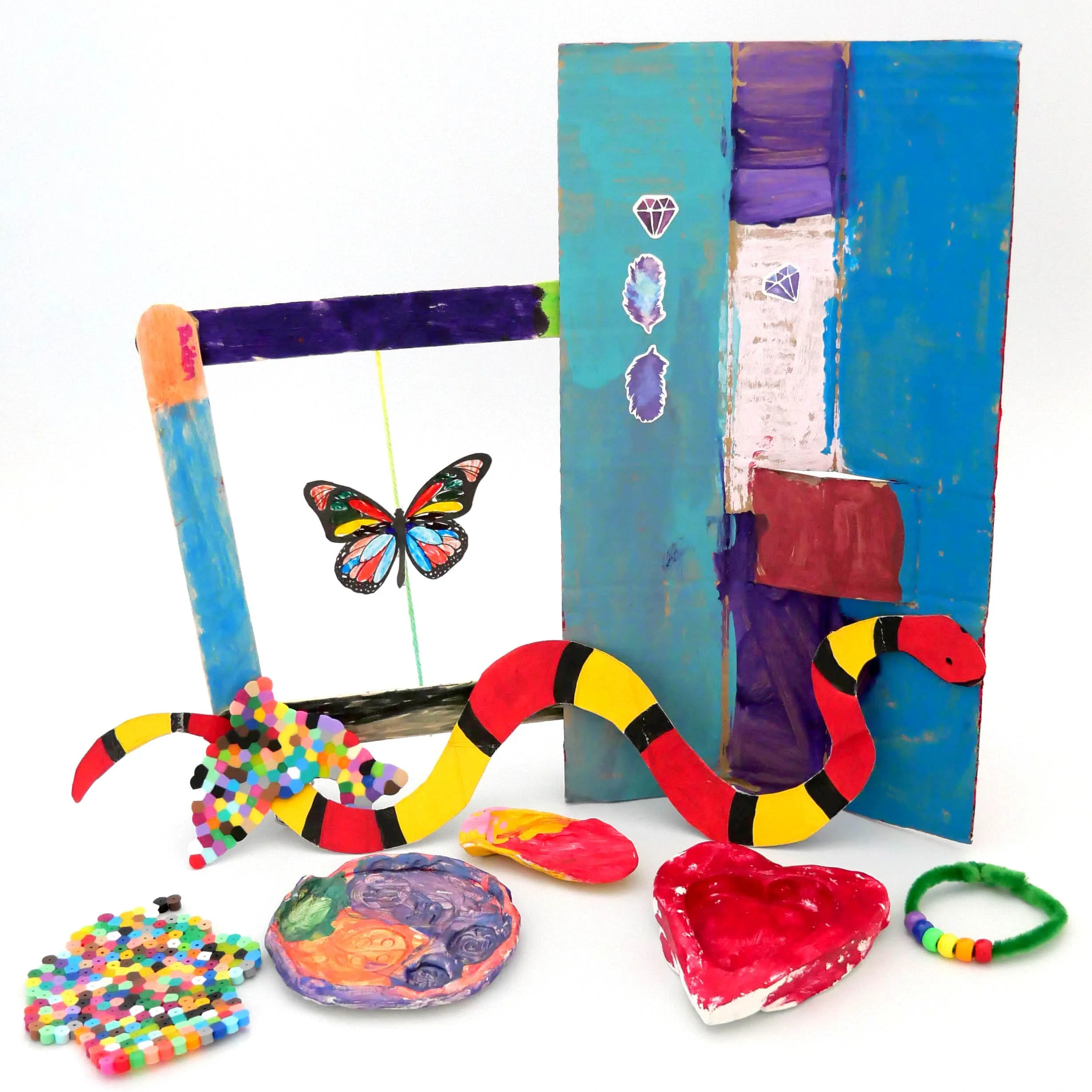 Colorful hand-painted wooden blocks with stickers of rocks, feathers, and diamonds, surrounded by small colorful beads and painted shells on a white background.