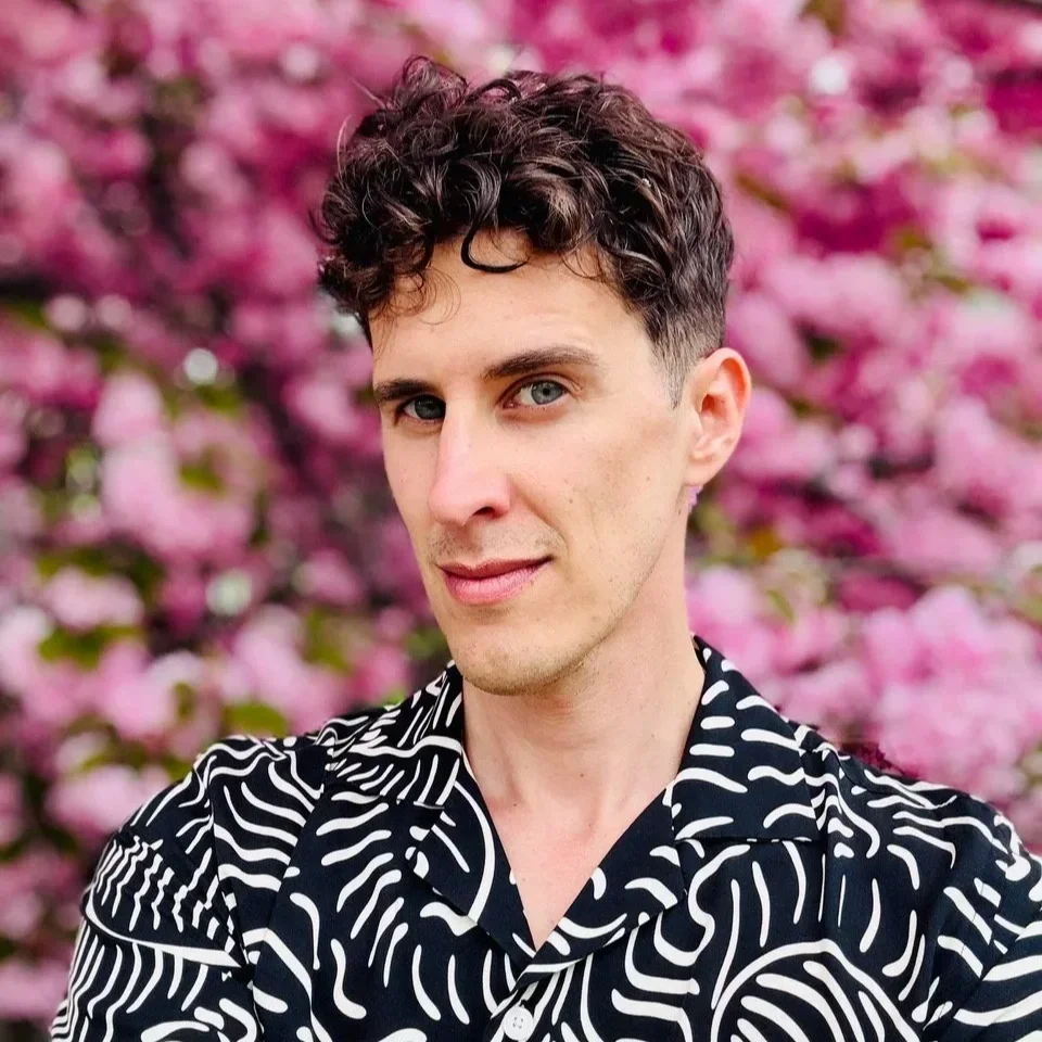 Portrait of author Michael Solis in front of blooming pink flowers