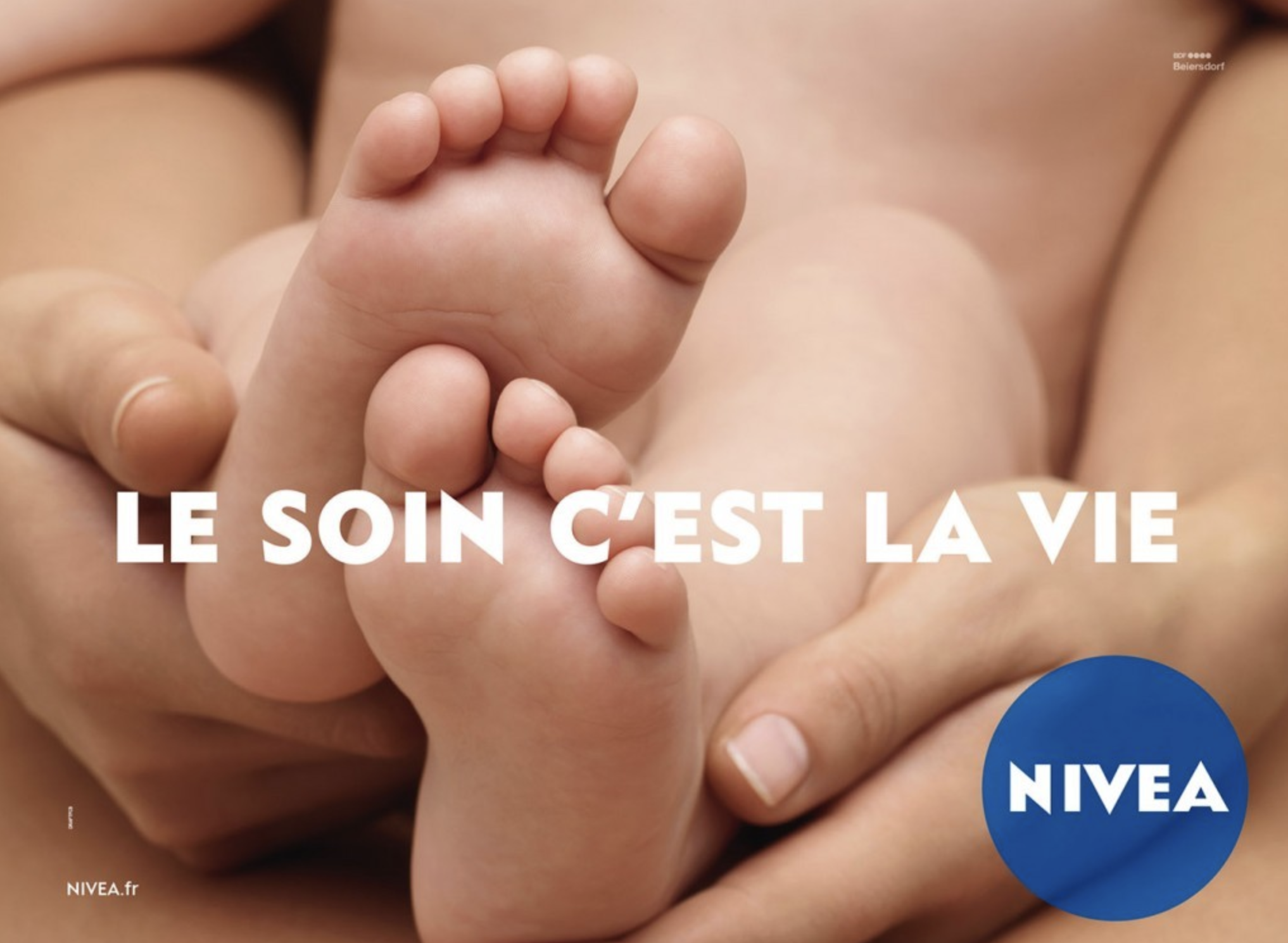 Un bébé tenant le doigt d'un adulte, avec le slogan en français "Le soin c'est la vie" écrit en blanc sur l'image.