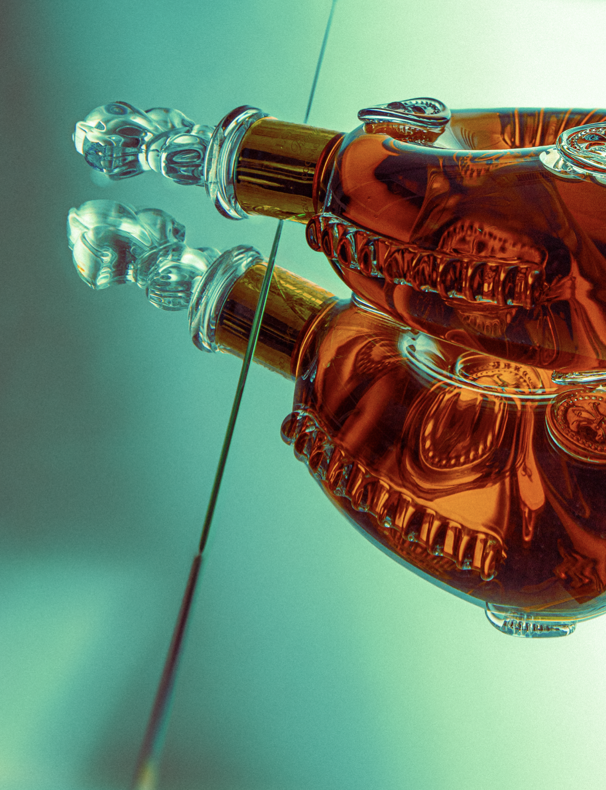 Verre de parfum avec un bouchon en verre décoratif, posé sur une surface réfléchissante.