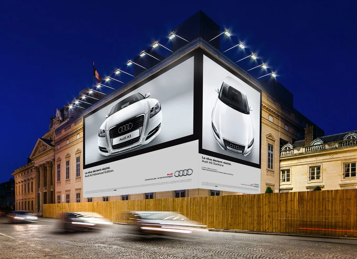 Panneau publicitaire lumineux sur un bâtiment historique représentant deux voitures Audi, une Audi A3 et une Audi A5 Darkline, avec textes en français