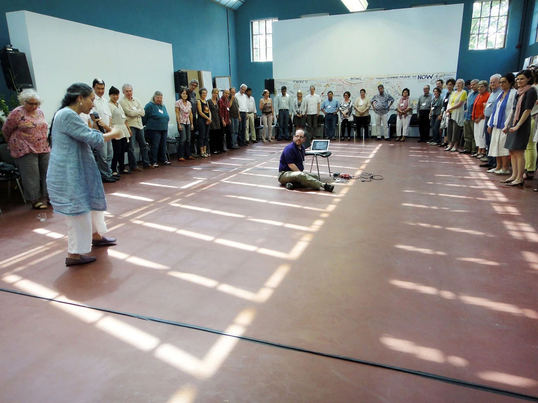 Figure 10: Containers. A final circle led by Arawana Hayashi during the Presencing Masterclass,   with the drawing on the far wall. Berlin, Germany. 2012.