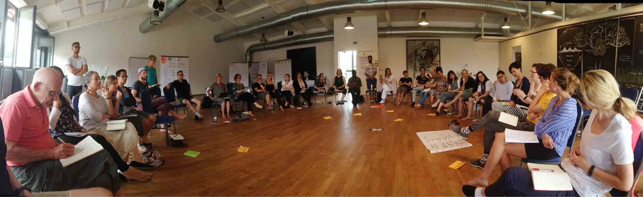 Figure 26: Setup. An example of a container in the room that infused the drawing with a certain quality of care. See the paper on the far right. I sat with the group in the circle until moved to draw, at which point I would rise and work on the wall.